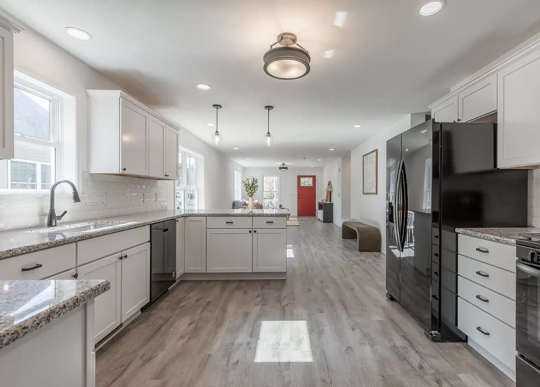 Bright modern kitchen with white cabinets, gray countertops, island, and stainless steel appliances