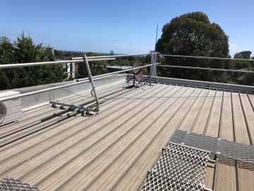 Metal roof with scaffolding for safety, blue sky and trees in the background.