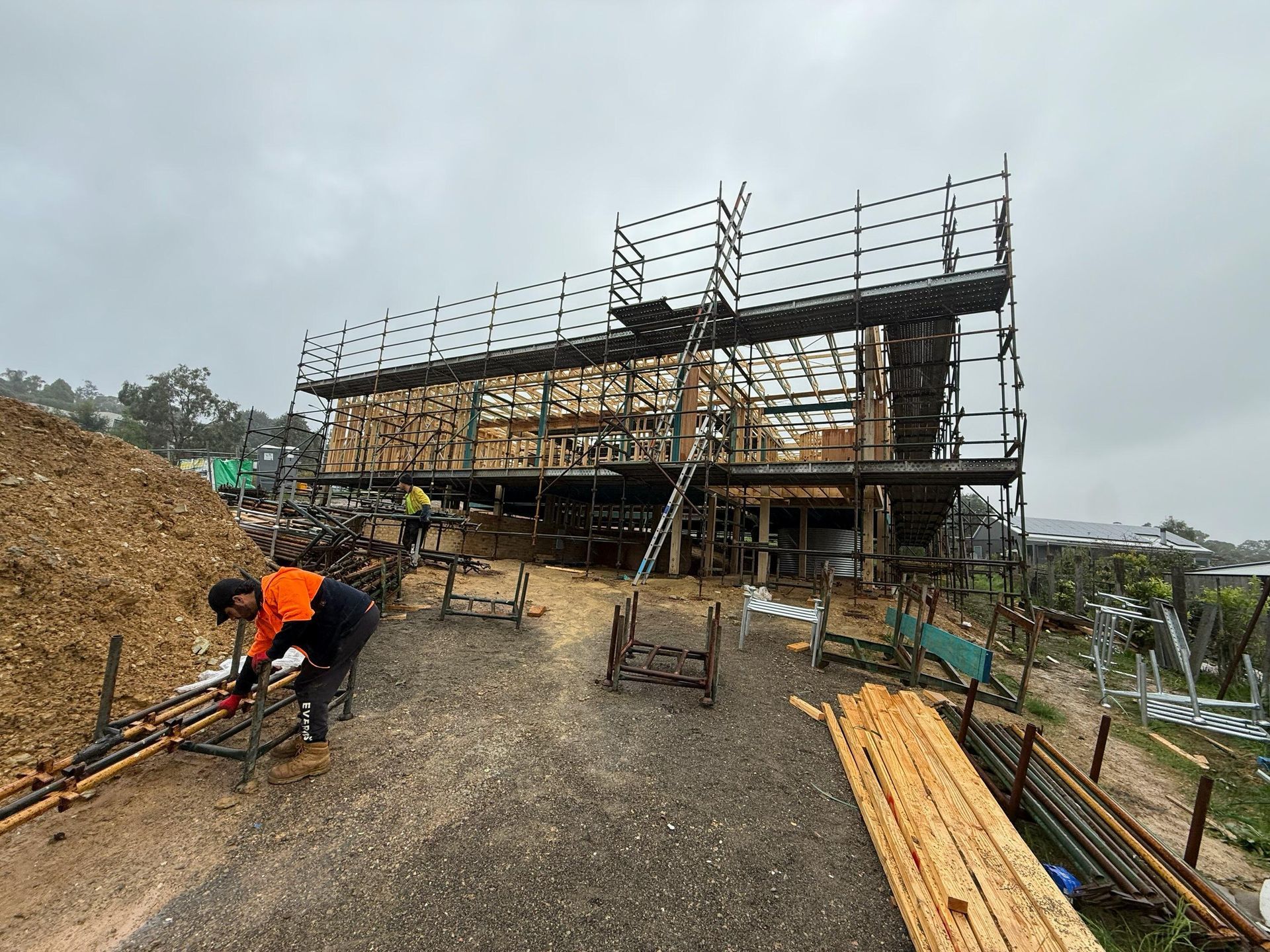 Construction worker applying plaster to building exterior from scaffolding.