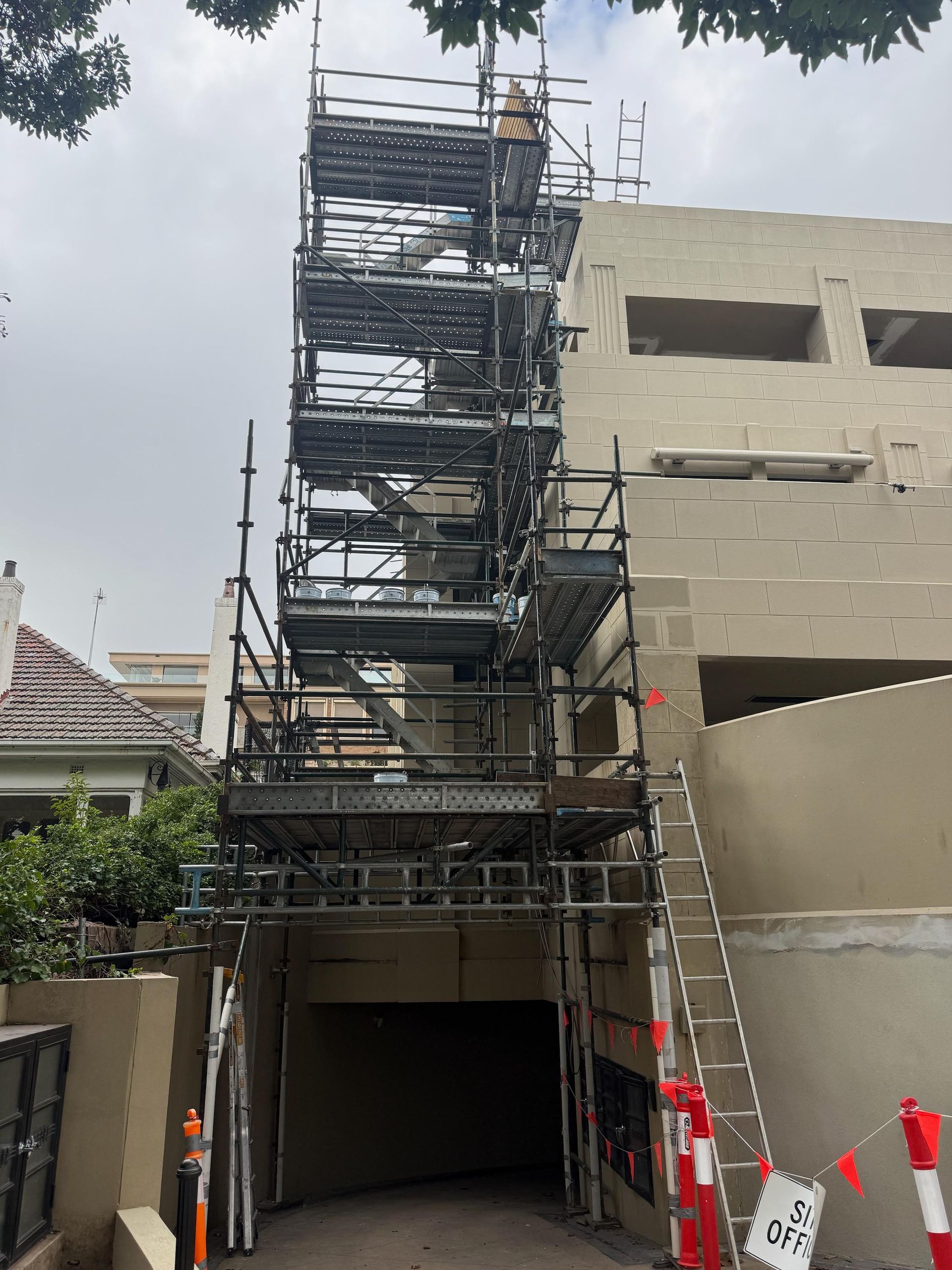Three construction workers on scaffolding, carrying wooden beams.
