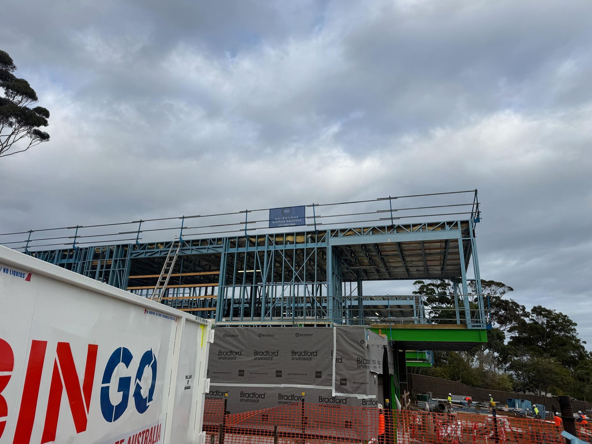 Building facade covered in white protective netting and scaffolding. Sunny outdoor setting.