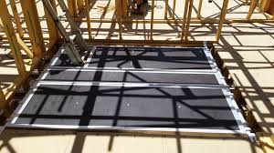 Scaffolding along a white building wall with a partial view of the sky.