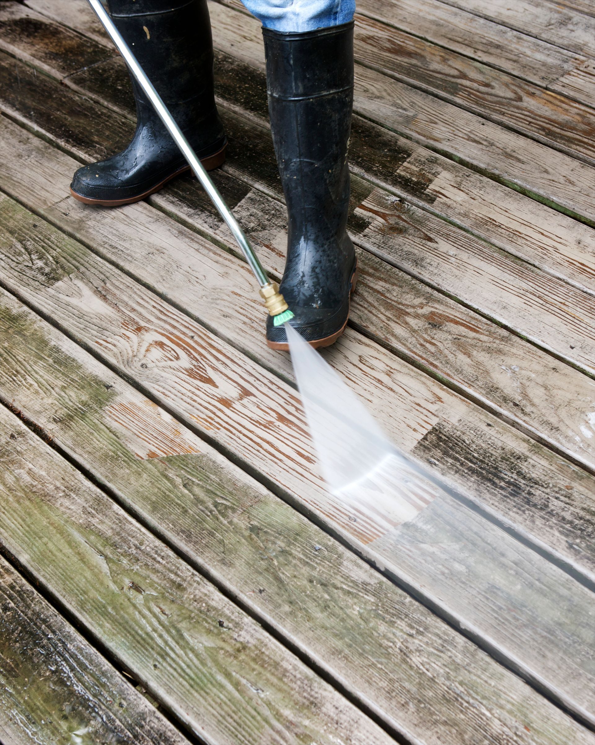 A person is using a high-pressure washer to clean a wooden deck — Cave Spring, GA — Straight Shooter Pressure Washing