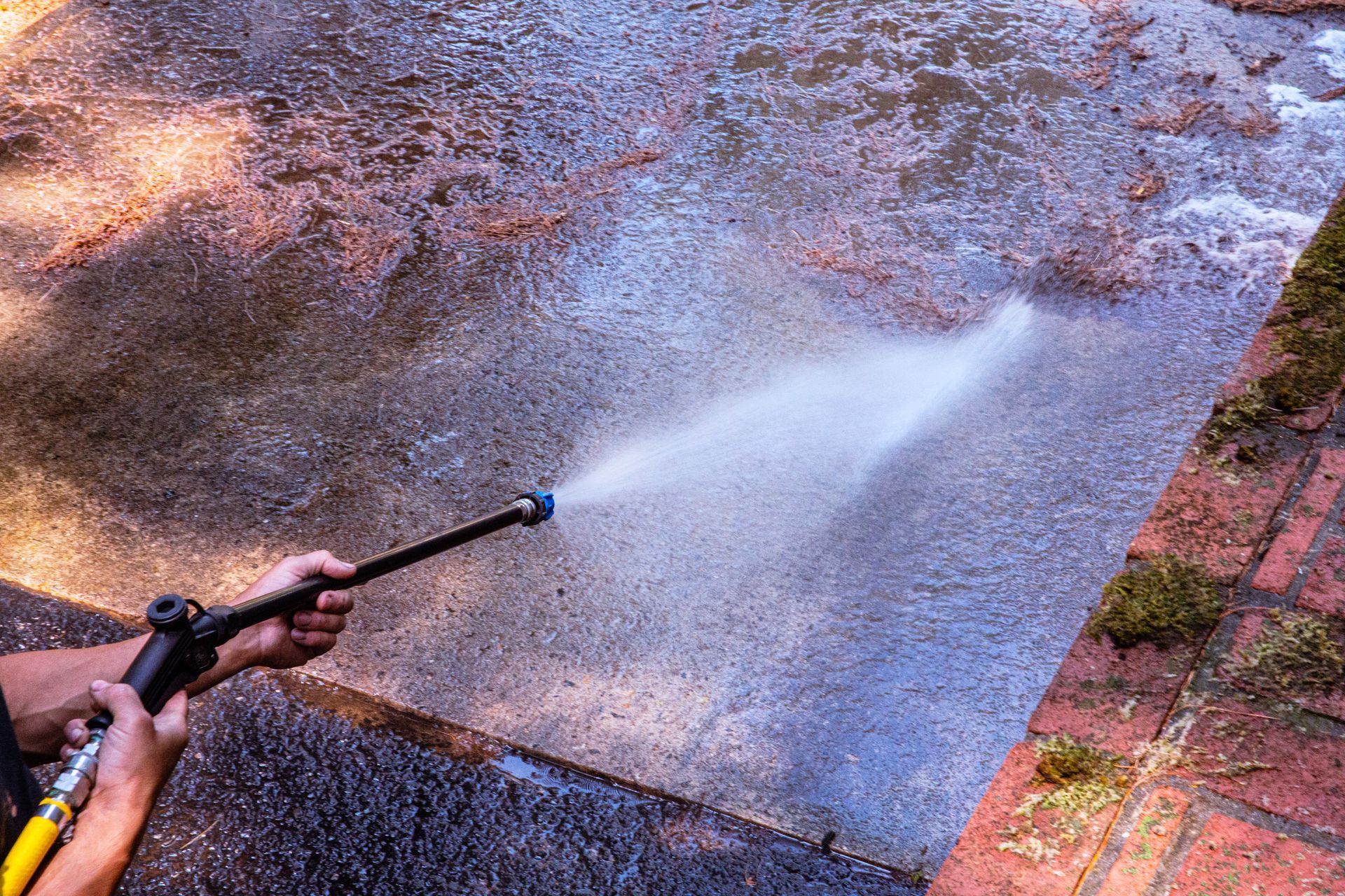 A person is using a high-pressure washer to clean a sidewalk — Cave Spring, GA — Straight Shooter Pressure Washing