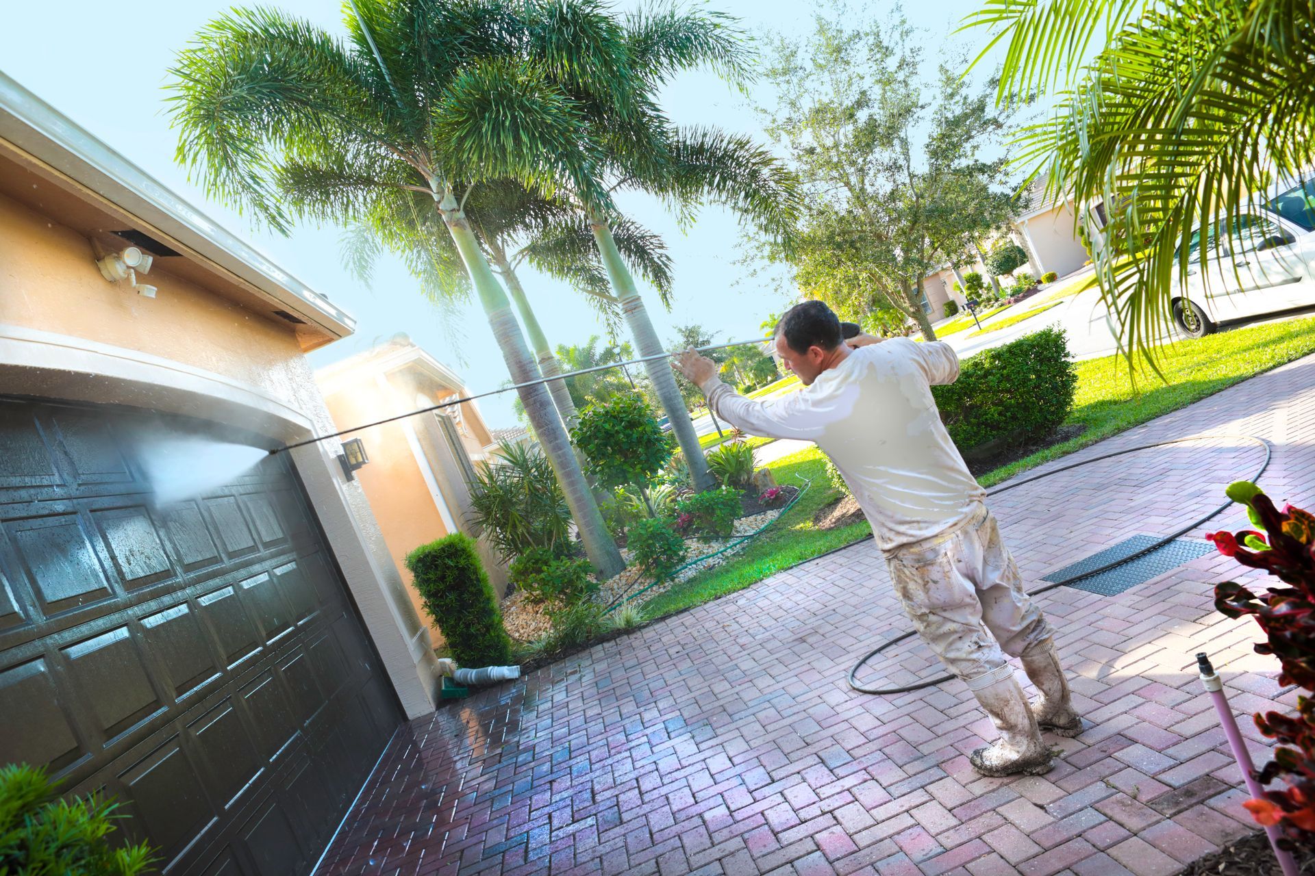 A man is cleaning the driveway of a house with a pressure washer — Cave Spring, GA — Straight Shooter Pressure Washing