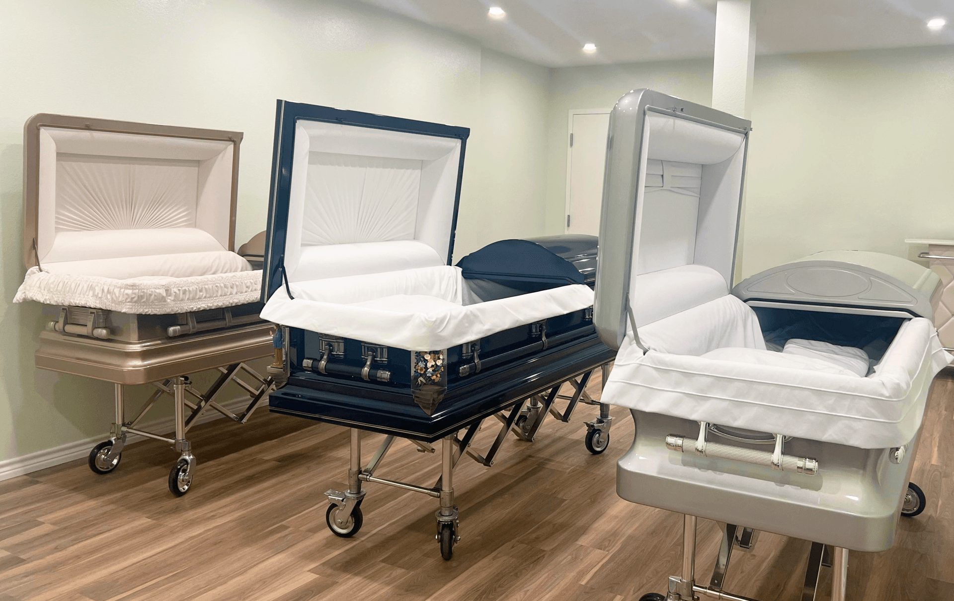 Four hospital beds with white bedding in a bright room with wood flooring