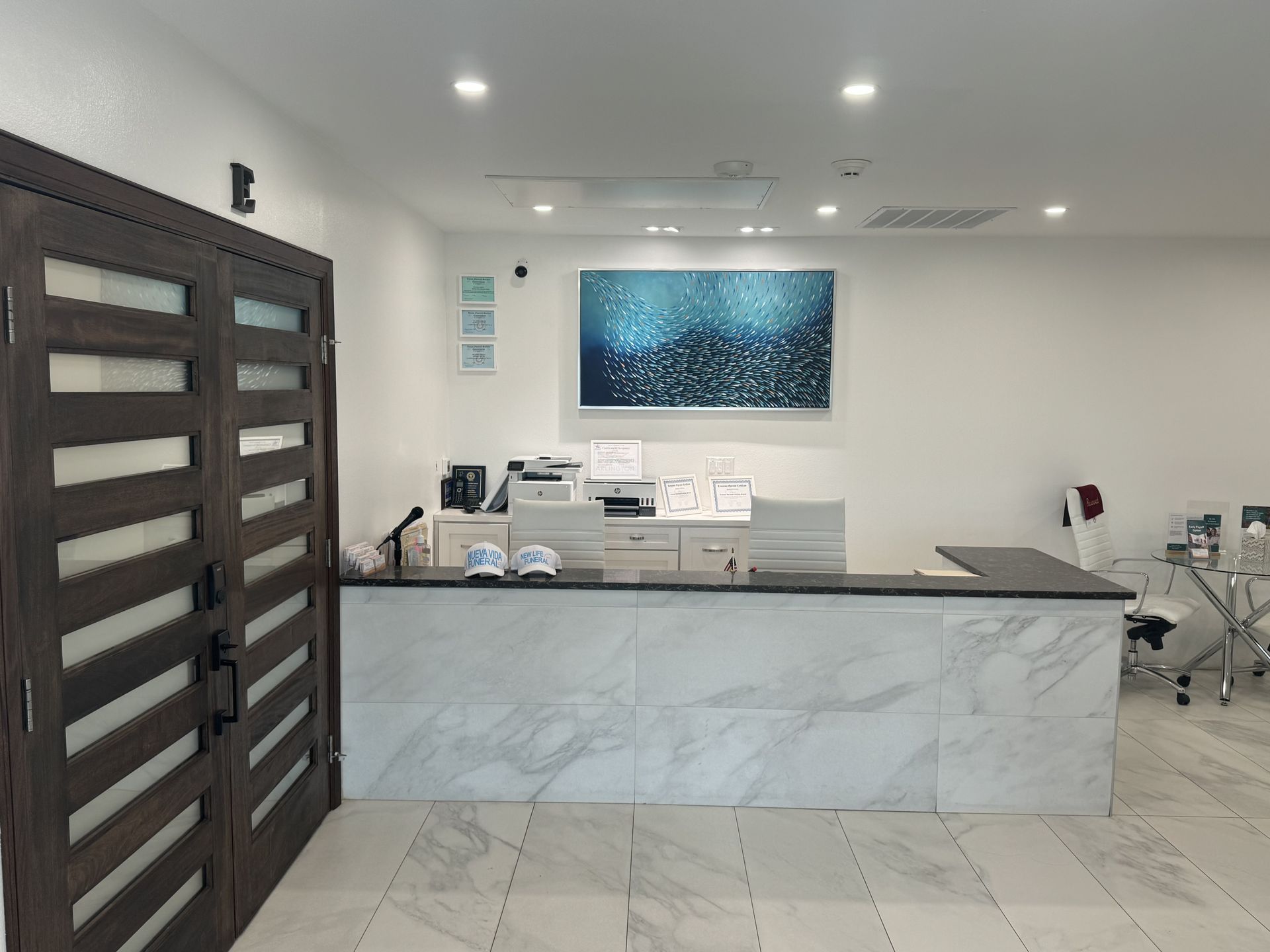 Modern medical reception desk with marble counter, white walls, chairs, and dark wooden door