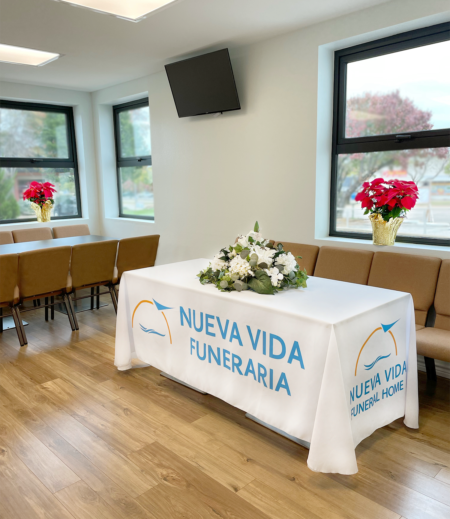 Funeral home room with a floral-covered table and chairs, labeled “NUEVA VIDA FUNERARIA”