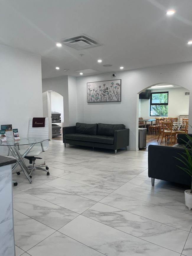 Modern hotel lobby with marble front desk, tiled floor, and wood-paneled entrance door