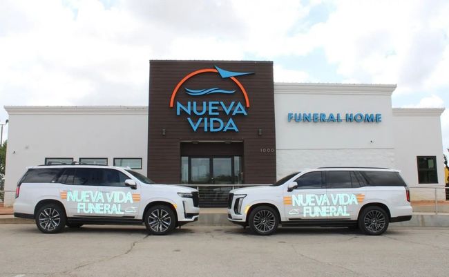 Nueva Vida Funeral Home building with two white service trucks parked in front