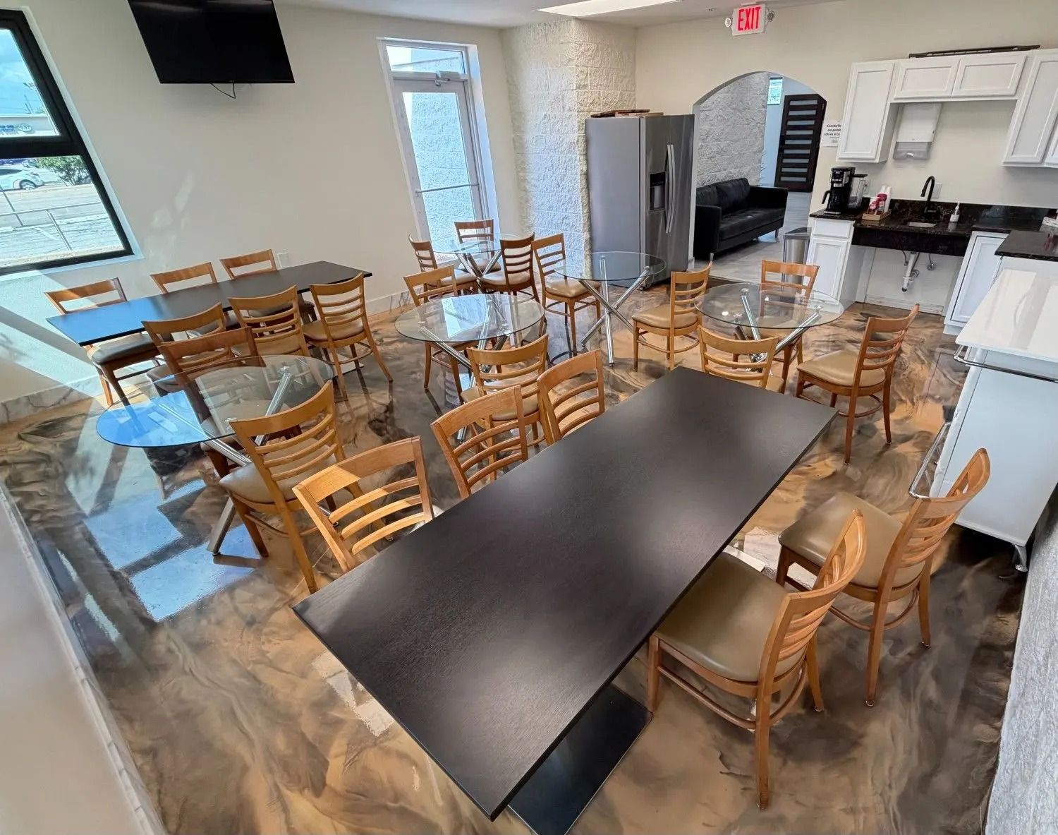 Empty dining area with wooden chairs around tables and a serving counter in the back