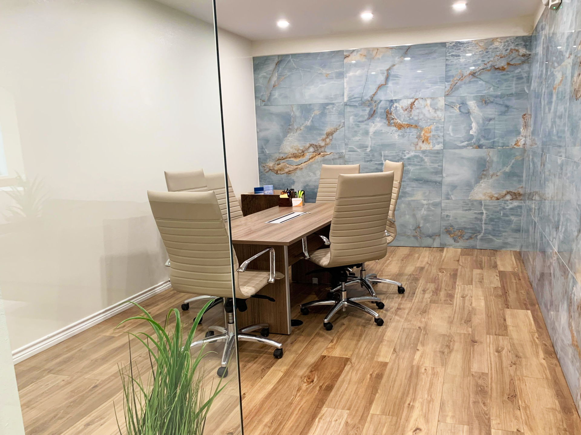Modern meeting room with wood table, beige chairs, and a blue marble accent wall