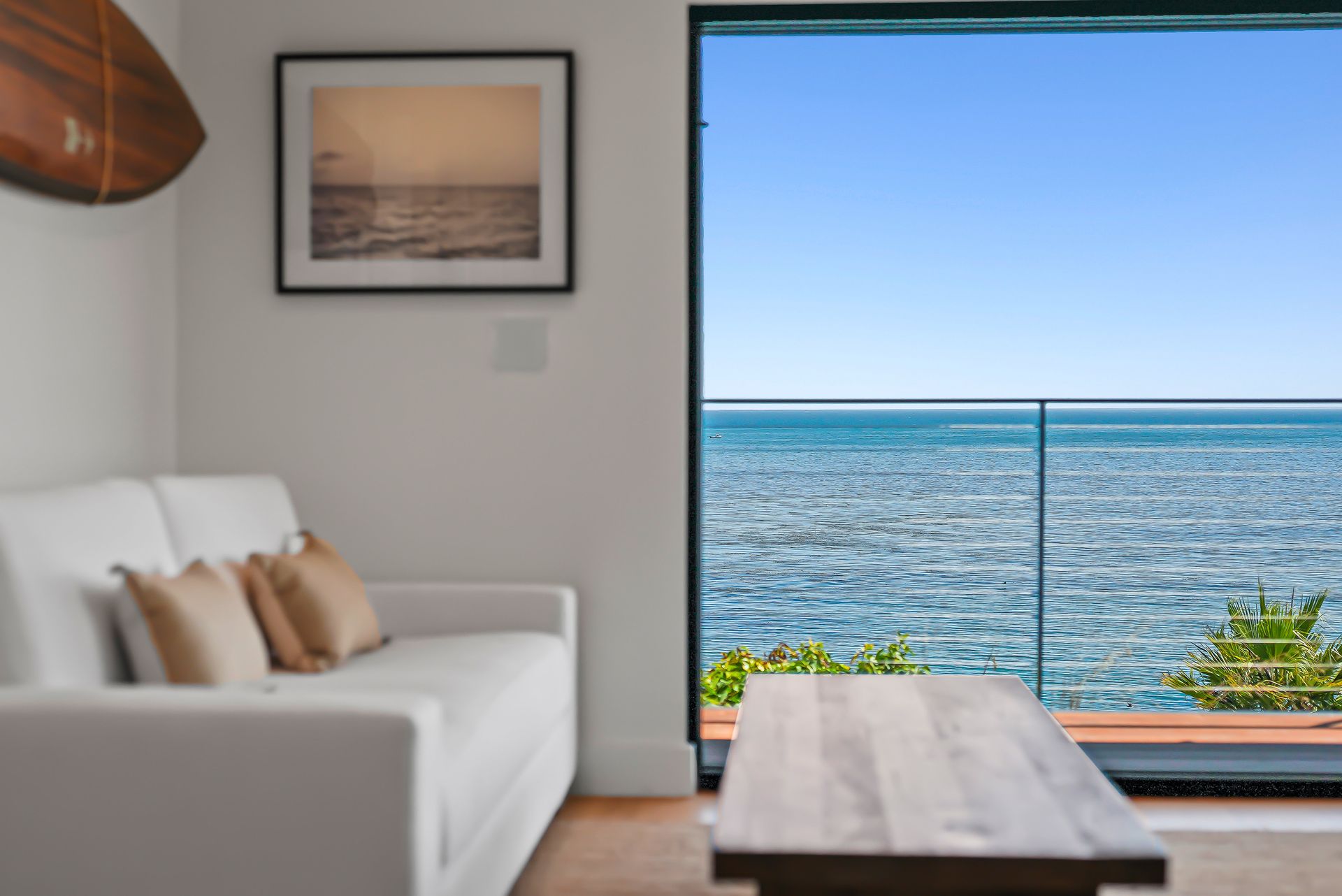 Bright living room with sofa and coffee table overlooking a calm ocean through a large window