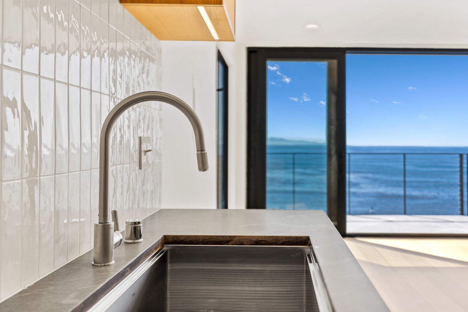 Modern kitchen sink with ocean view through large sliding glass doors