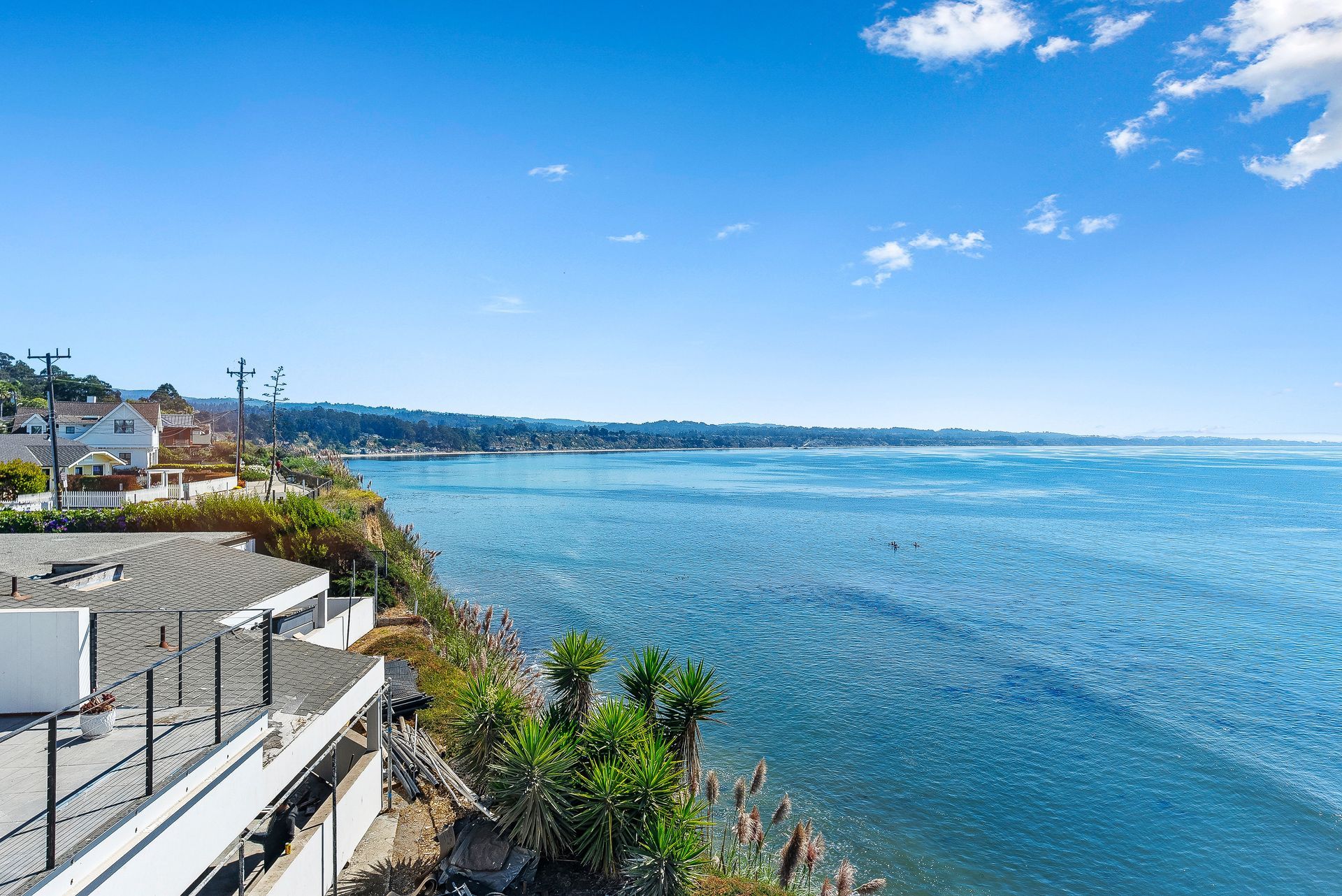 Bright blue ocean beside a cliffside walkway under a clear blue sky