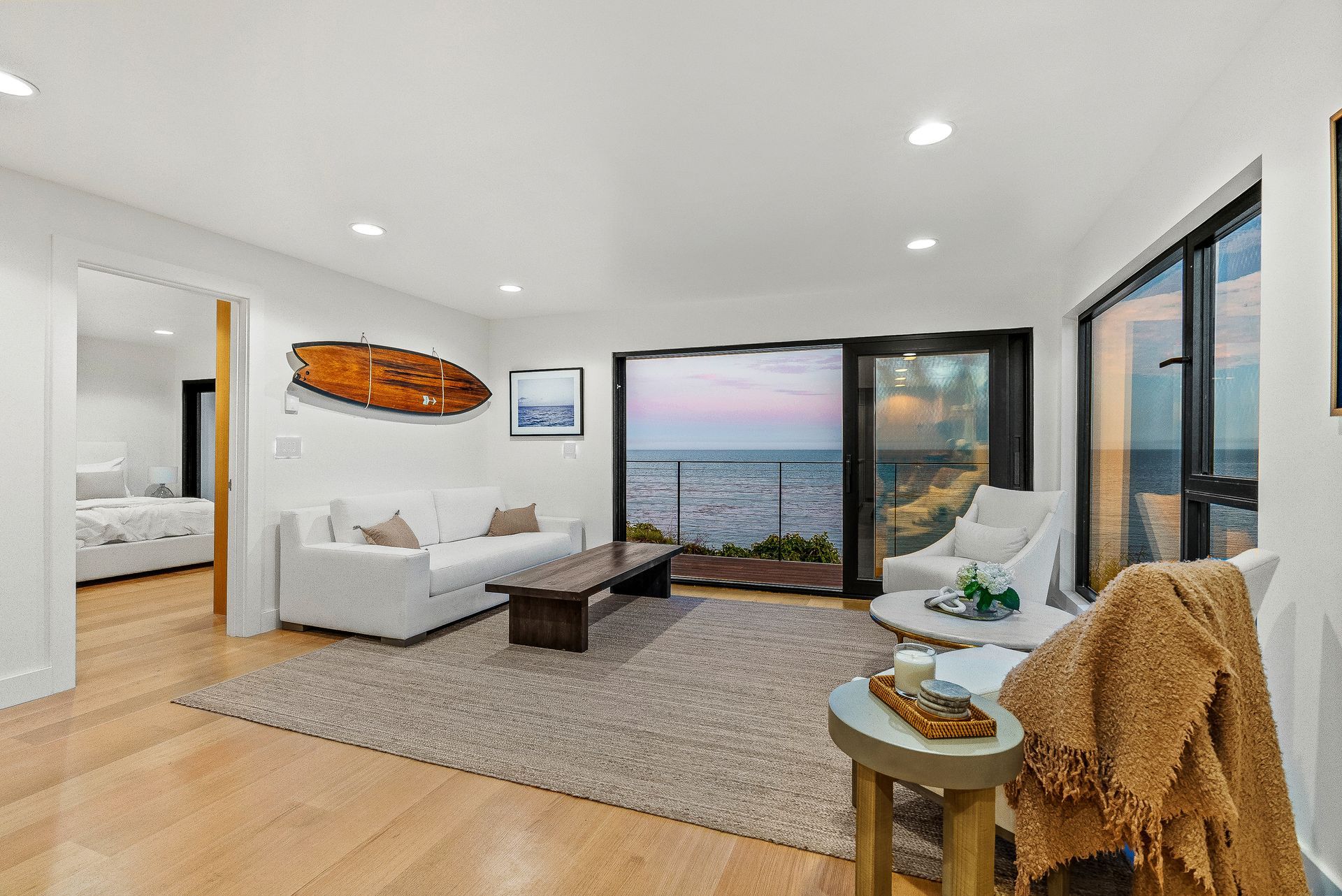 Bright living room with ocean view, white sofas, rug, and sliding glass doors to a balcony