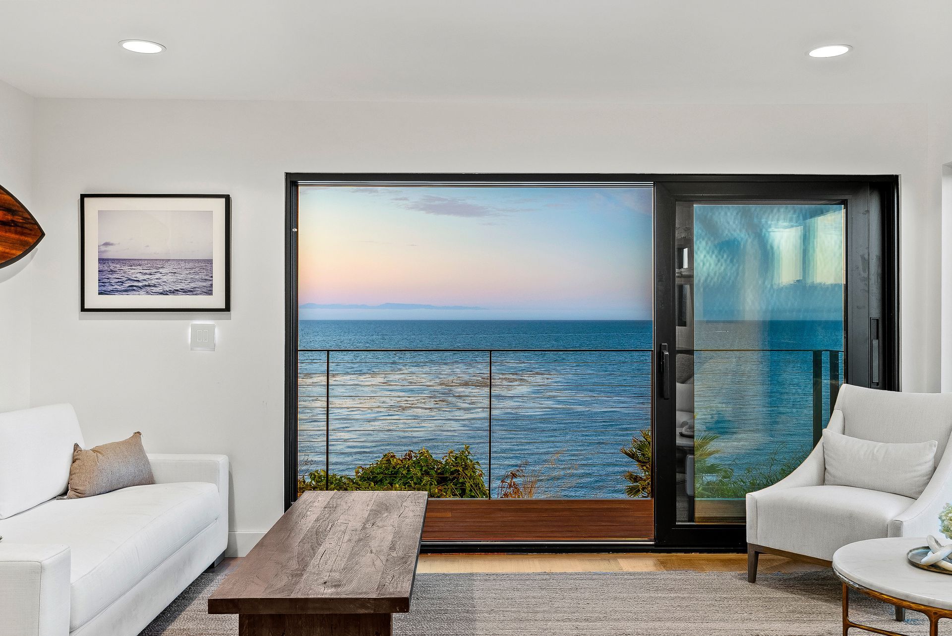 Modern living room with ocean view through a large sliding glass door at sunset