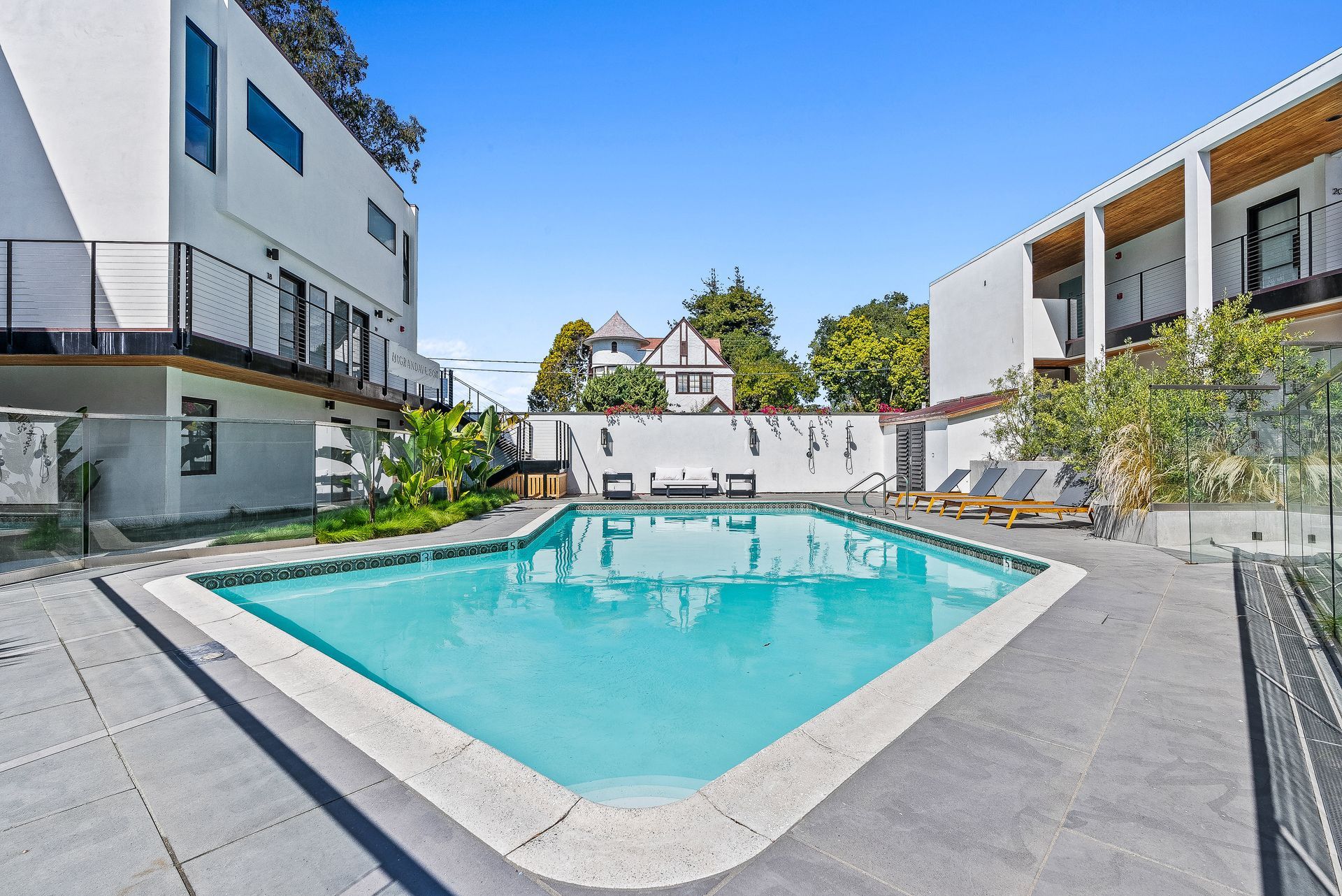 Courtyard pool with turquoise water, surrounded by modern white apartment buildings and lounge chairs
