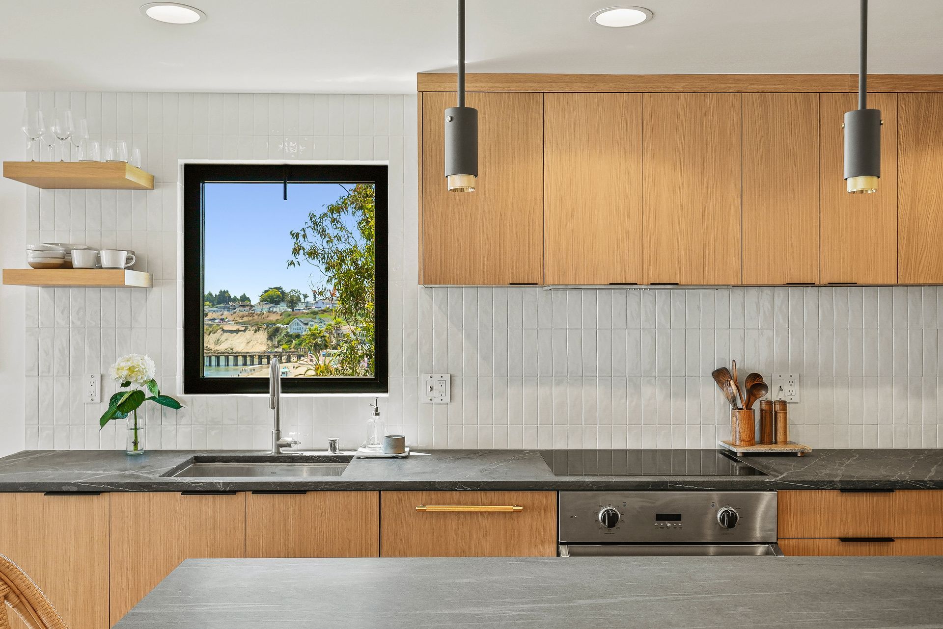 Modern kitchen with wood cabinets, gray countertop, and a window view of trees and sky