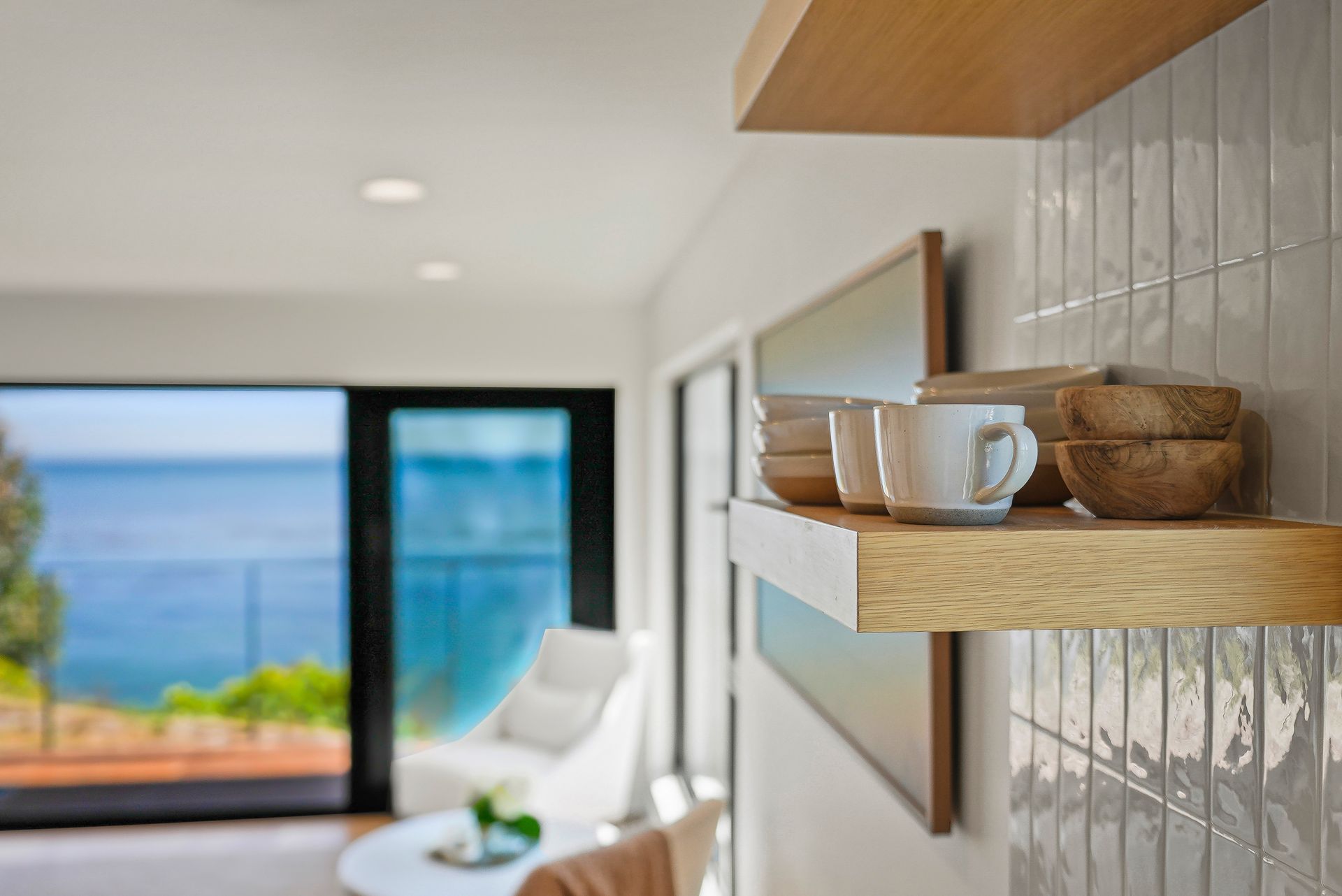 Modern room with wooden shelves, a mug, and a view of the ocean through large windows