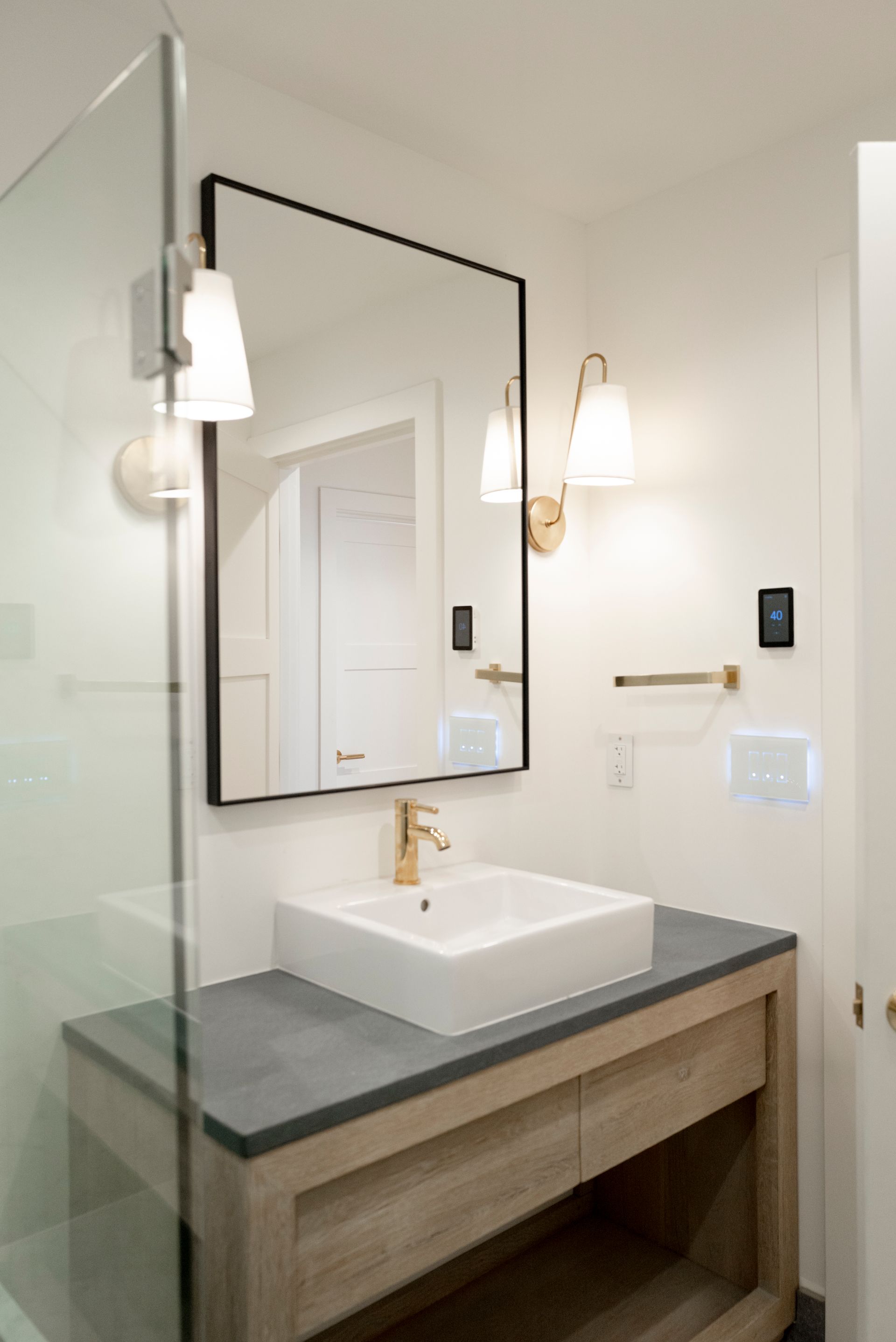Modern bathroom vanity with white sink, large mirror, and wall sconces on light walls.