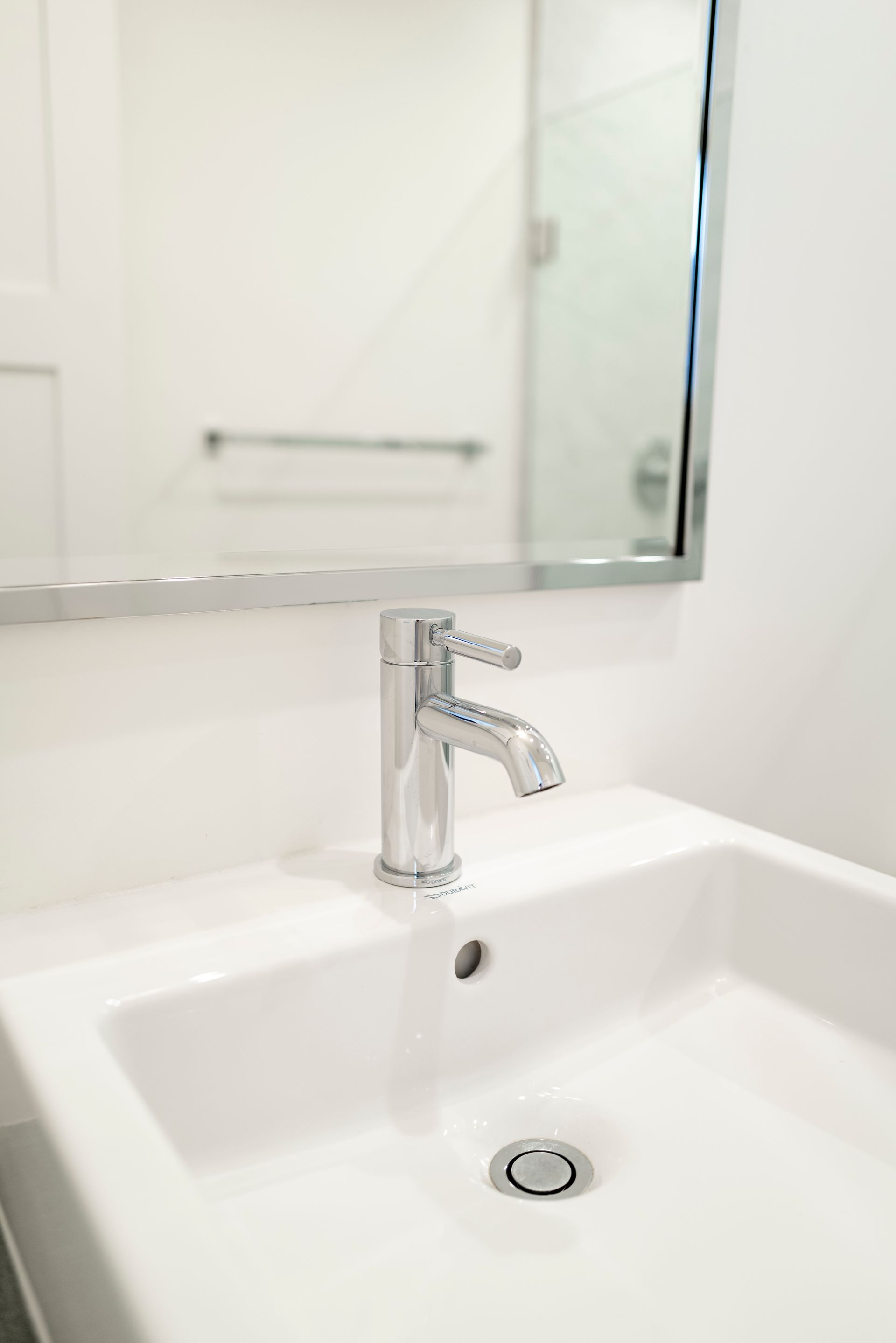 White bathroom sink with chrome faucet and mirror above it