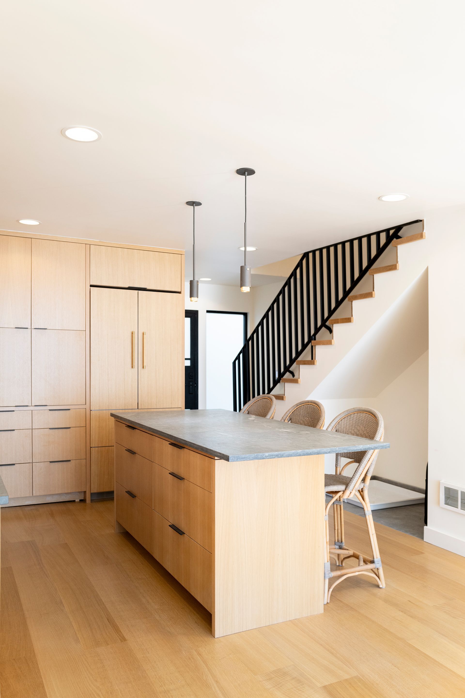Modern kitchen with wood island, granite countertop, and black staircase railing