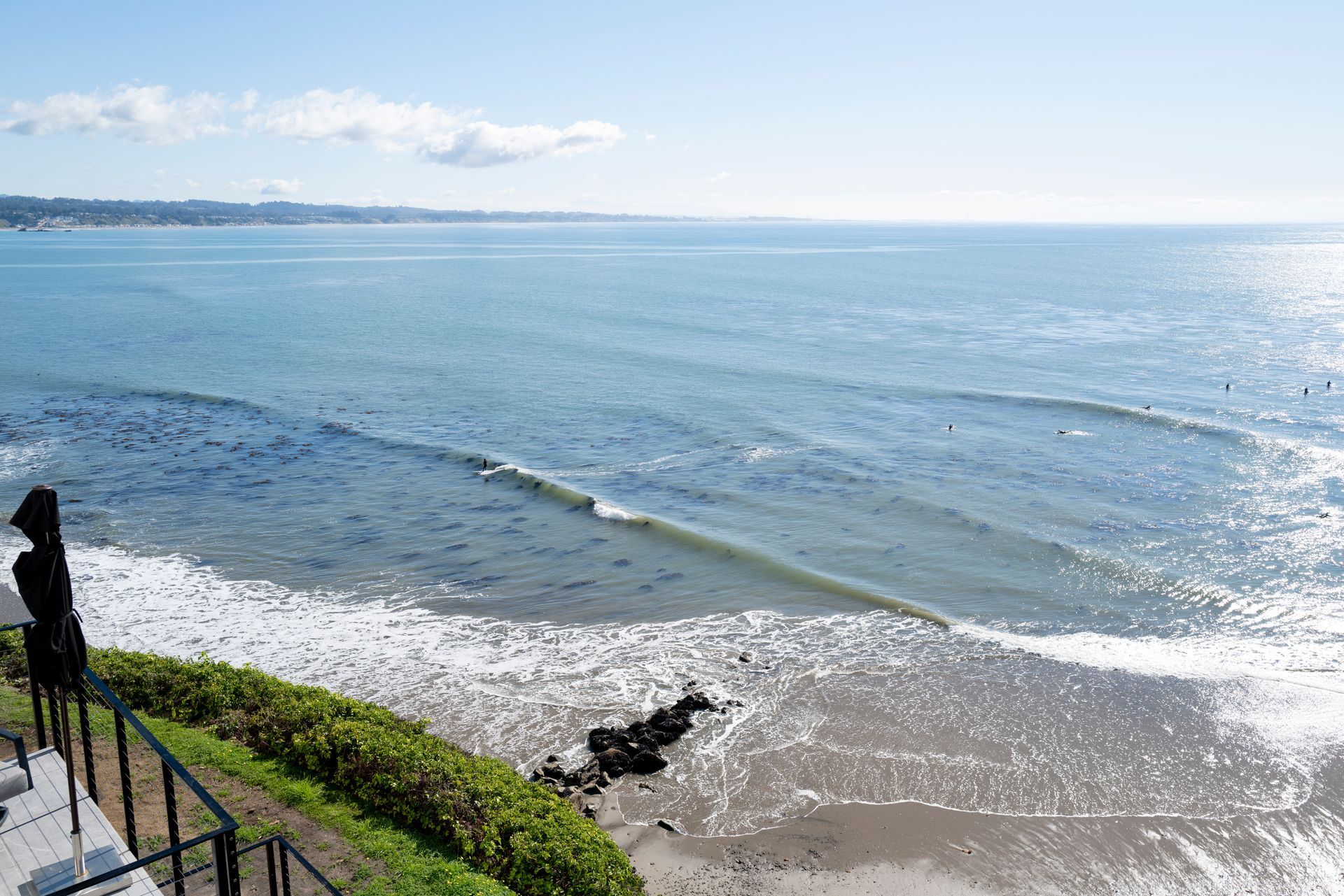 Bright ocean view from a cliffside walkway with waves sparkling on a sunny day