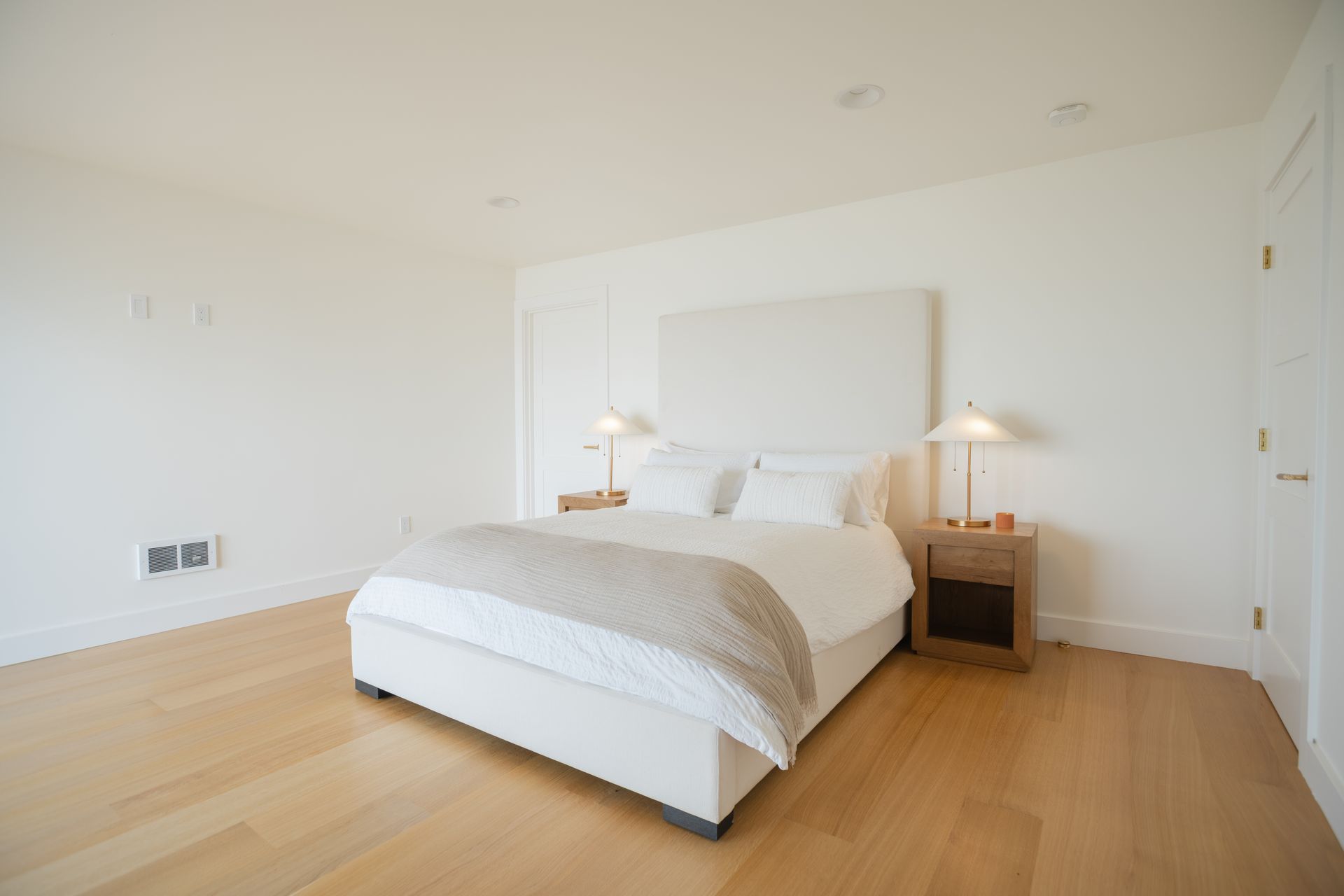 Minimal bedroom with a bed, two bedside lamps, and light wood flooring