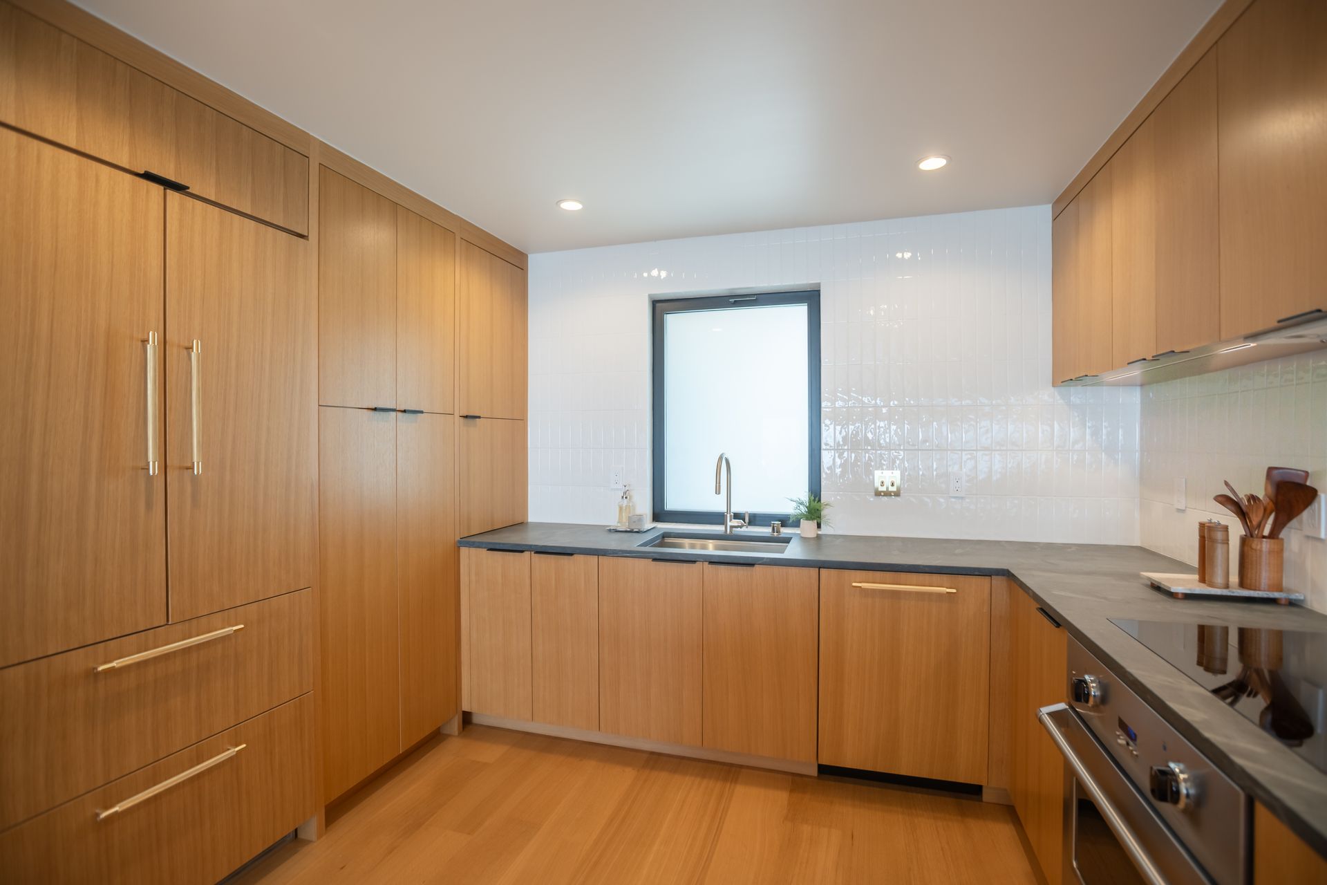 Modern kitchen with wood cabinets, white tile backsplash, stainless-steel appliances, and a window over the sink