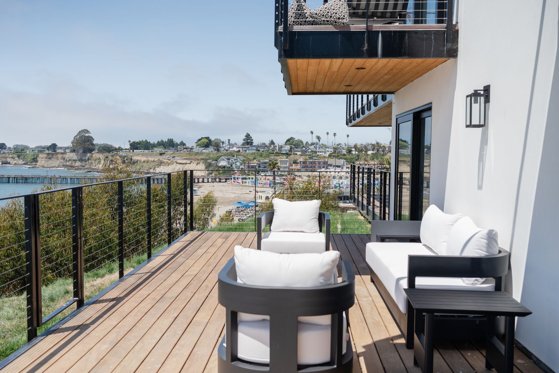 Modern apartment balcony with white patio furniture and city views