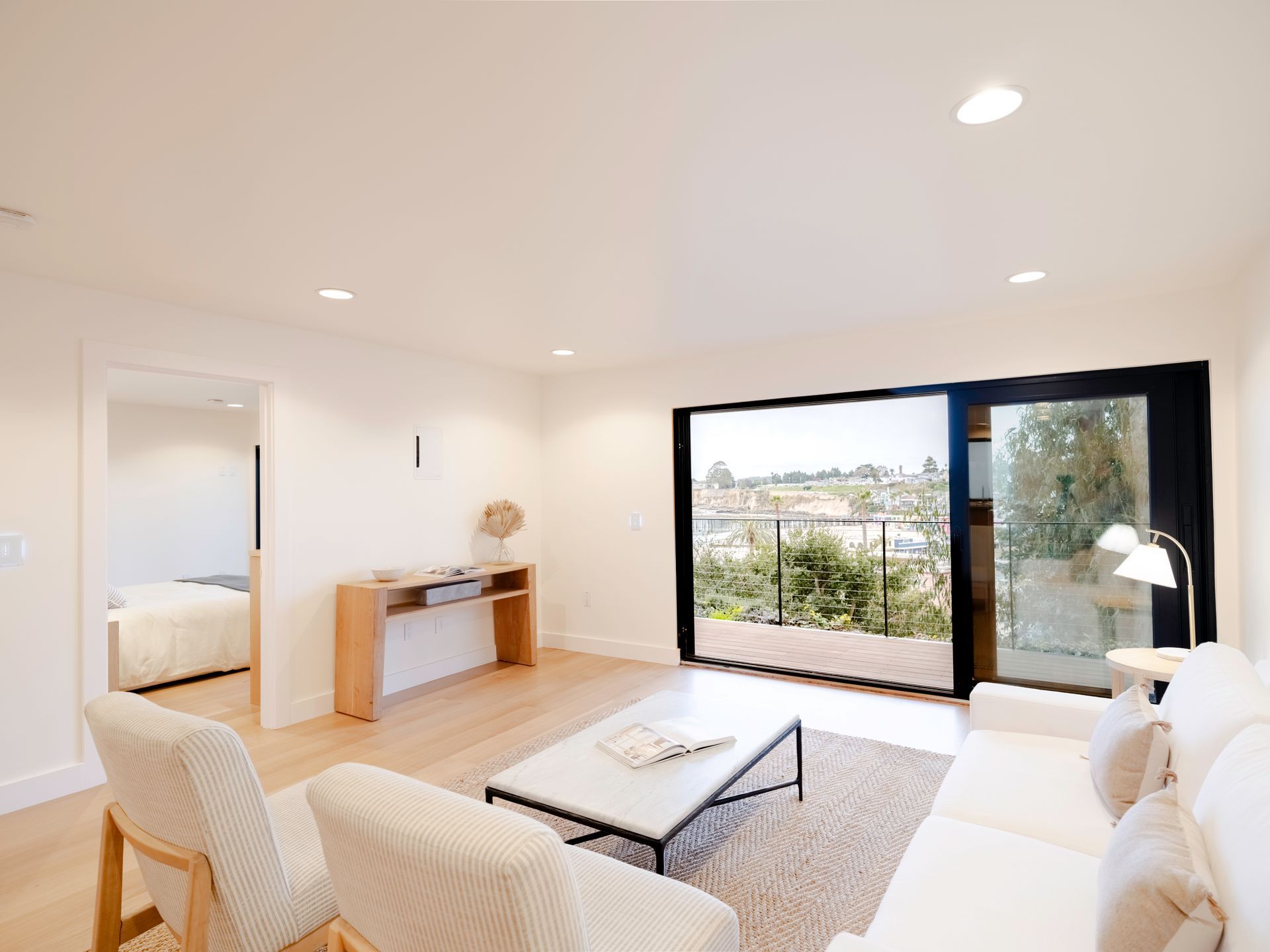 Bright modern living room with white furniture and large sliding doors overlooking a city view