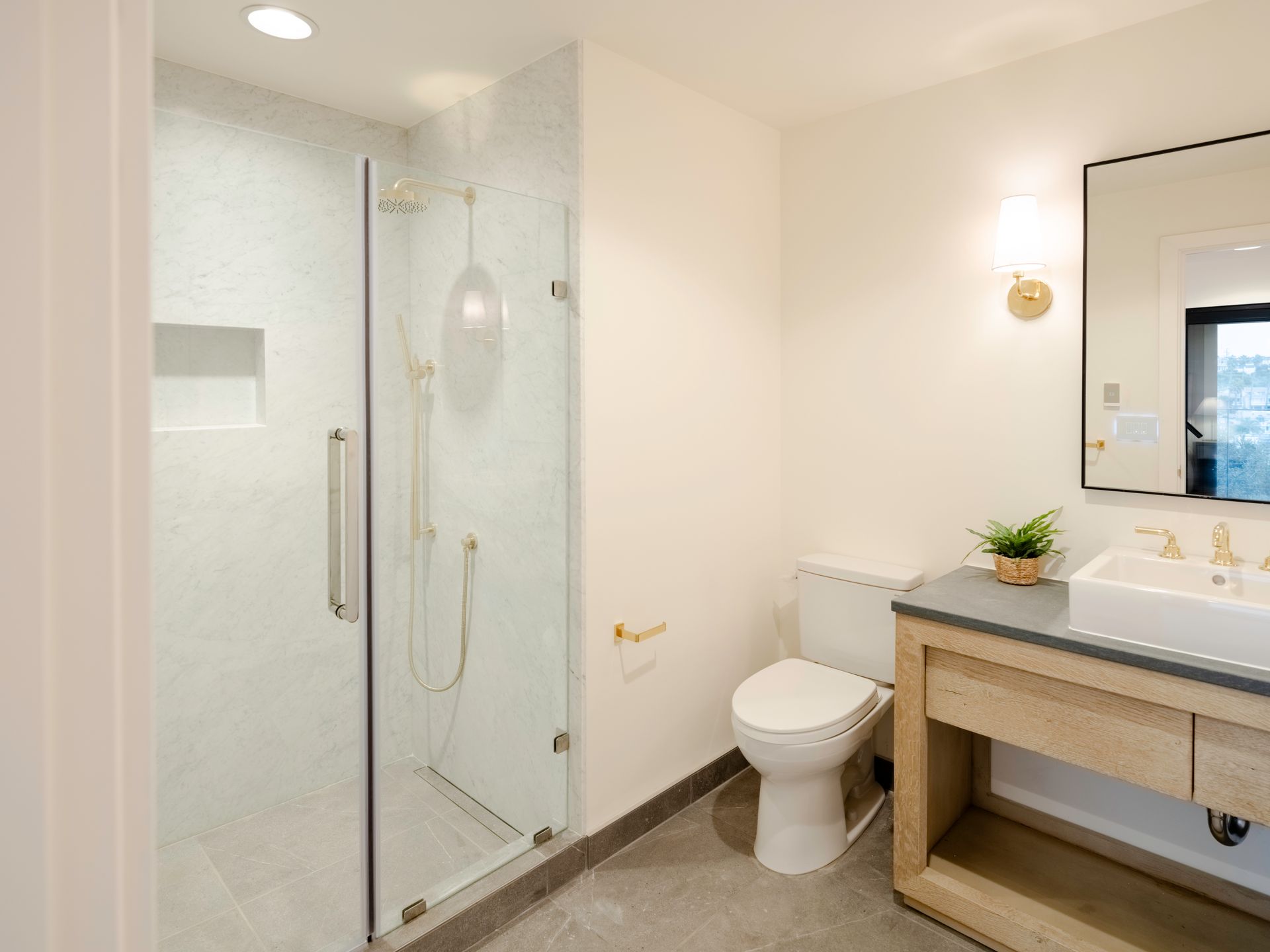 Modern white bathroom with glass shower, toilet, and vanity sink area