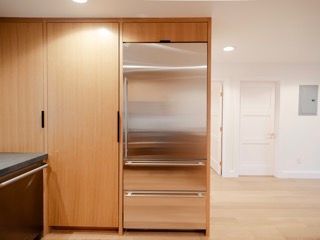 Modern kitchen with wood cabinets, stainless-steel fridge, and a doorway in the background