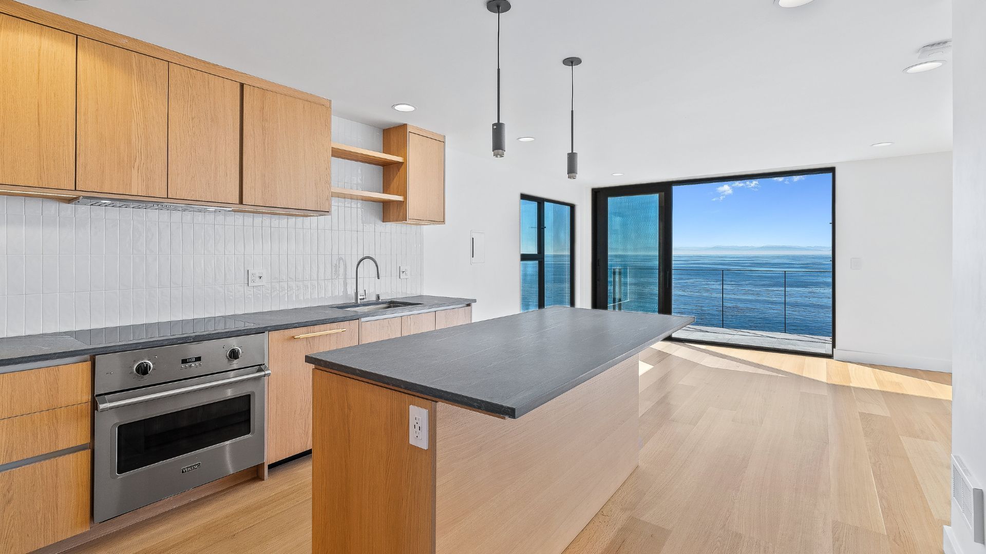 Bright modern kitchen with wood cabinets, island, and ocean-view windows.
