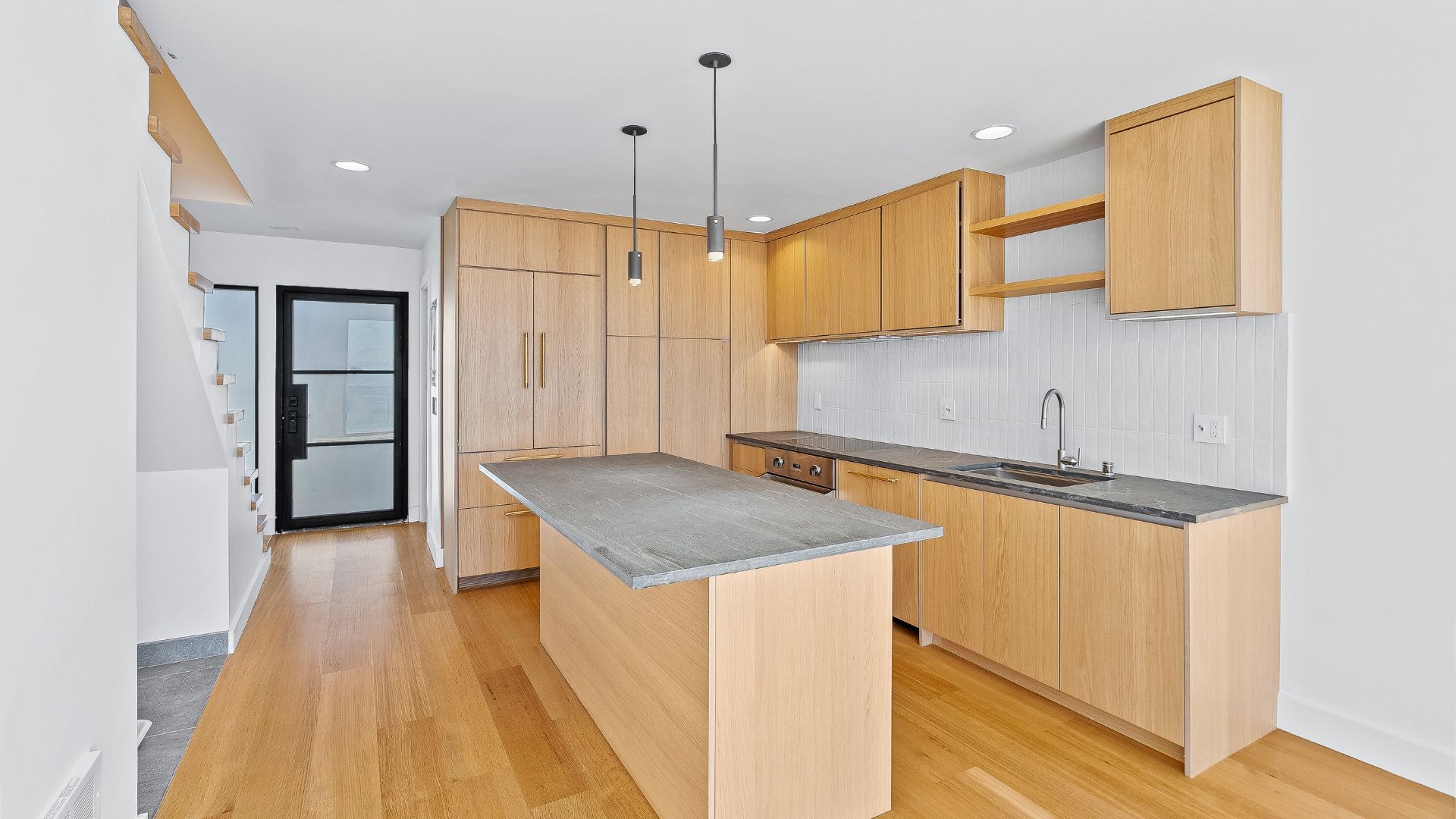 Bright modern kitchen with light wood cabinets, gray island countertop, and hardwood floors