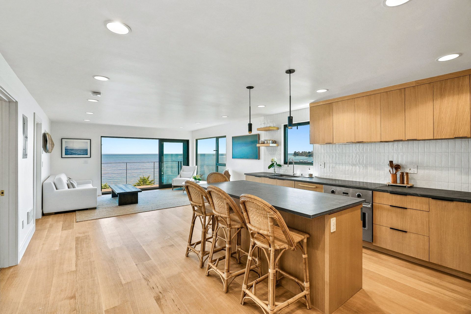 Modern kitchen and dining area with island, wood cabinets, and ocean view windows