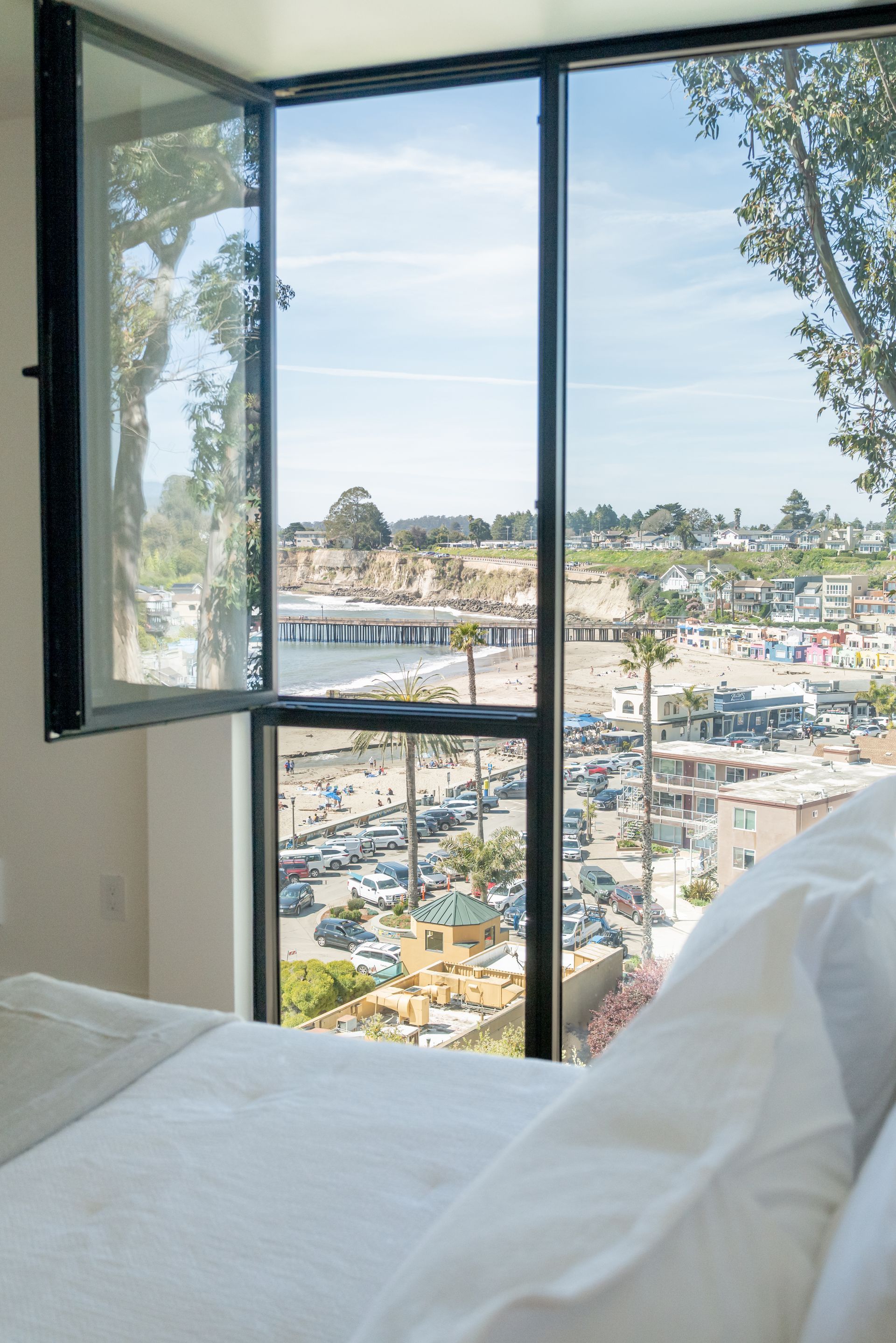 Bedroom window overlooking a marina and waterfront cityscape on a bright day