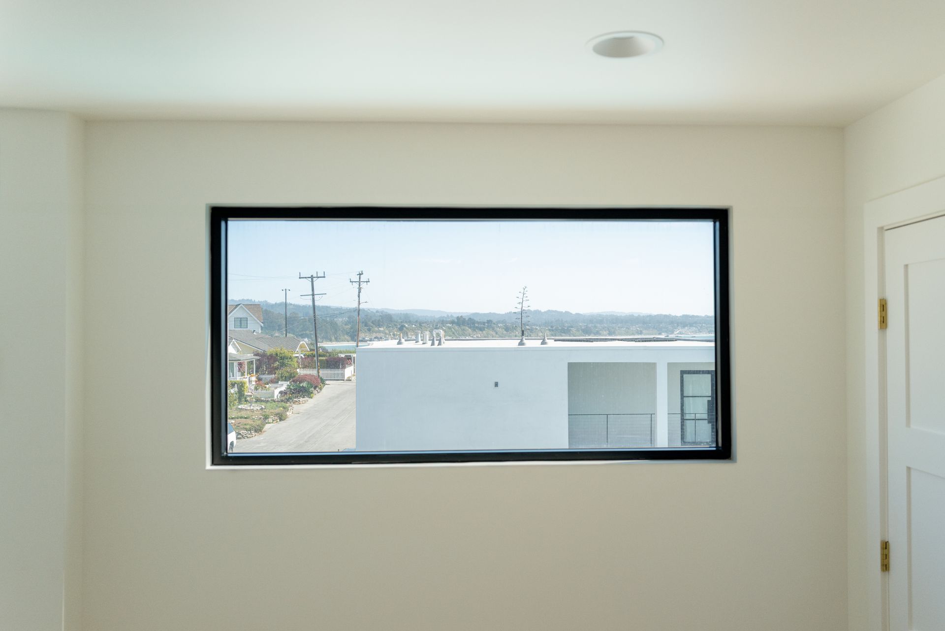 Empty room with a large window overlooking a waterfront and distant buildings
