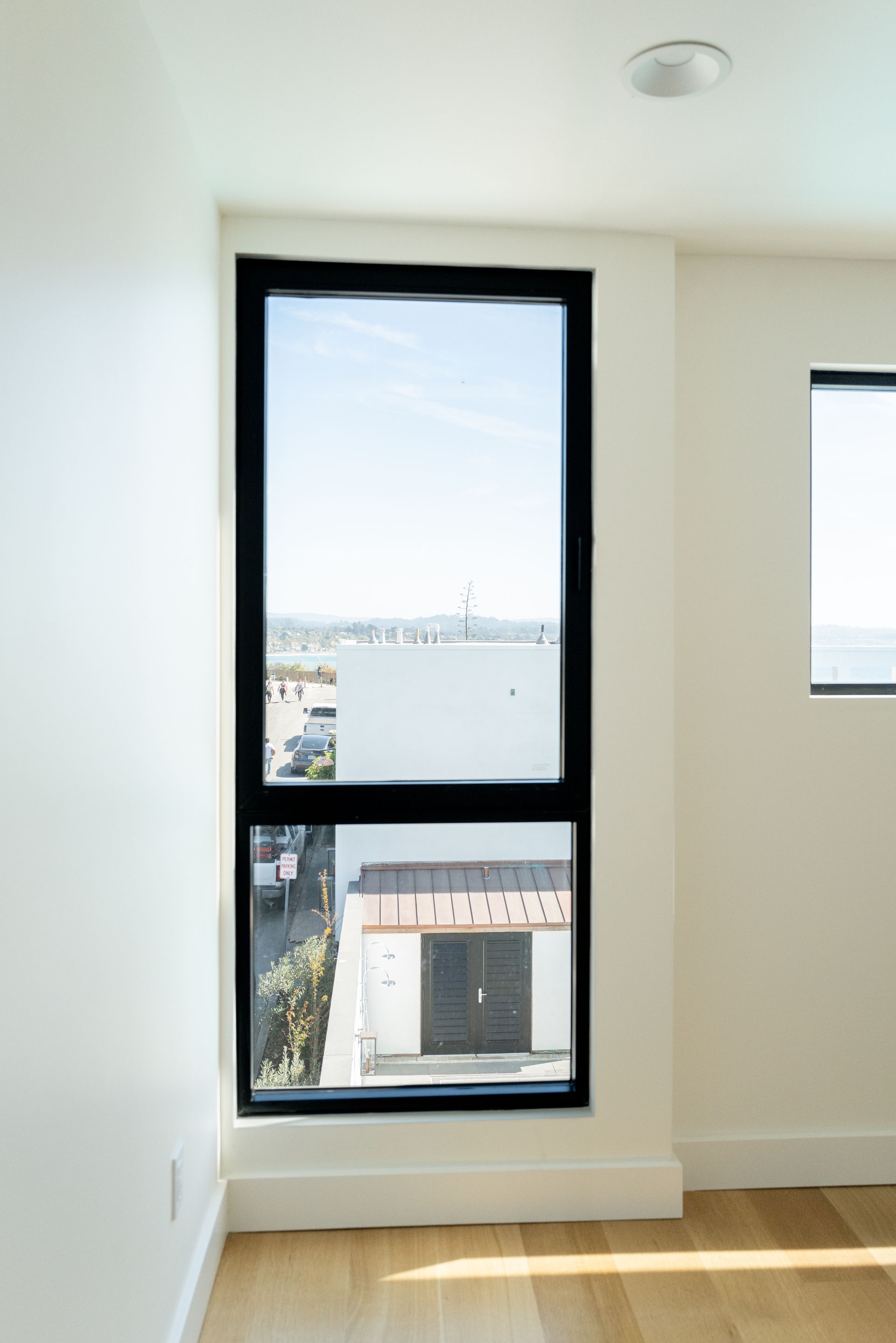 Empty room with two windows and a view of buildings outside
