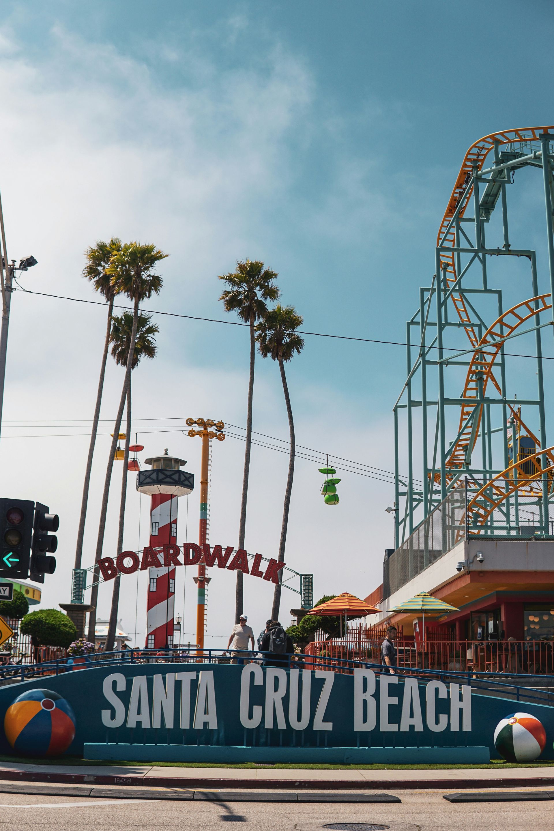 Santa Cruz Beach Boardwalk entrance with roller coaster, Ferris wheel, and palm trees under blue sky