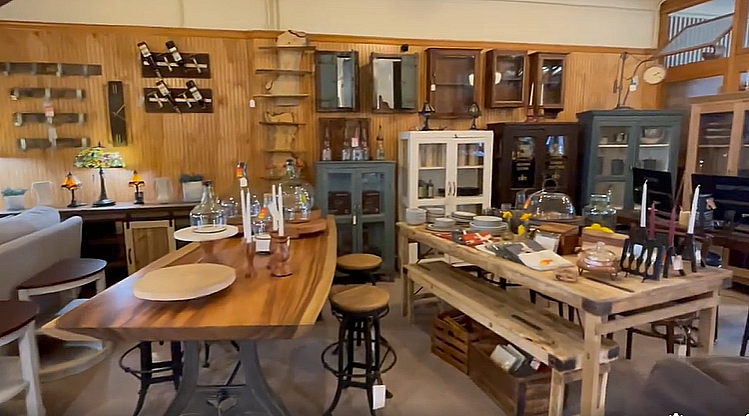 Interior of a furniture store with wooden tables, cabinets, and decorative items.