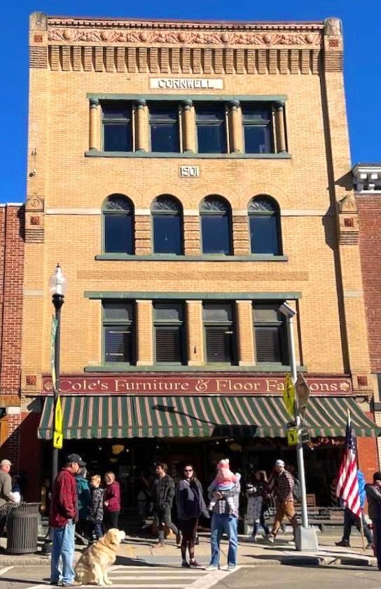 Cole's Furniture storefront, three stories of brick, with people gathered outside under a green awning.