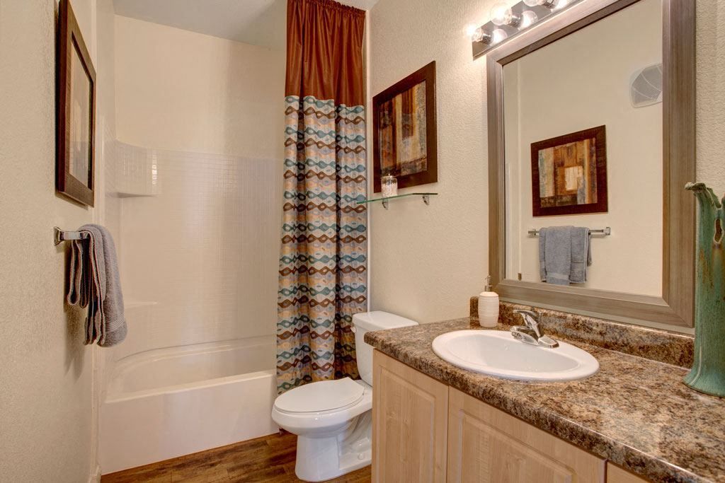 A bathroom with a toilet , sink , bathtub and mirror.