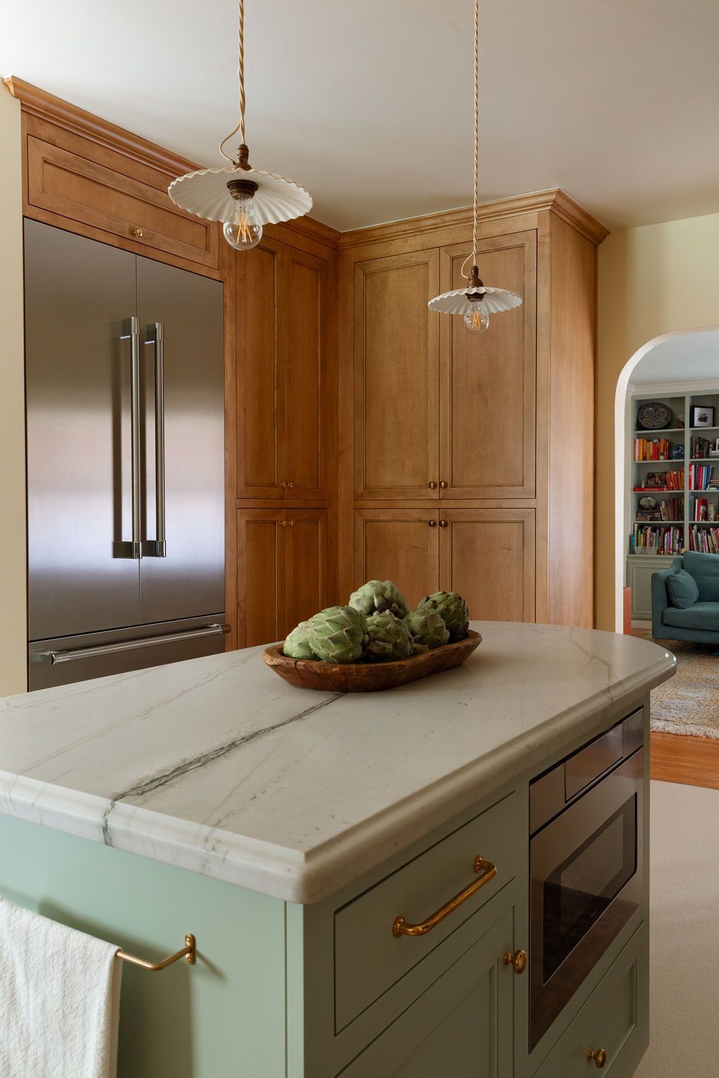 Luxury kitchen remodel featuring an island with a light stone countertop and warm wood cabinetry.
