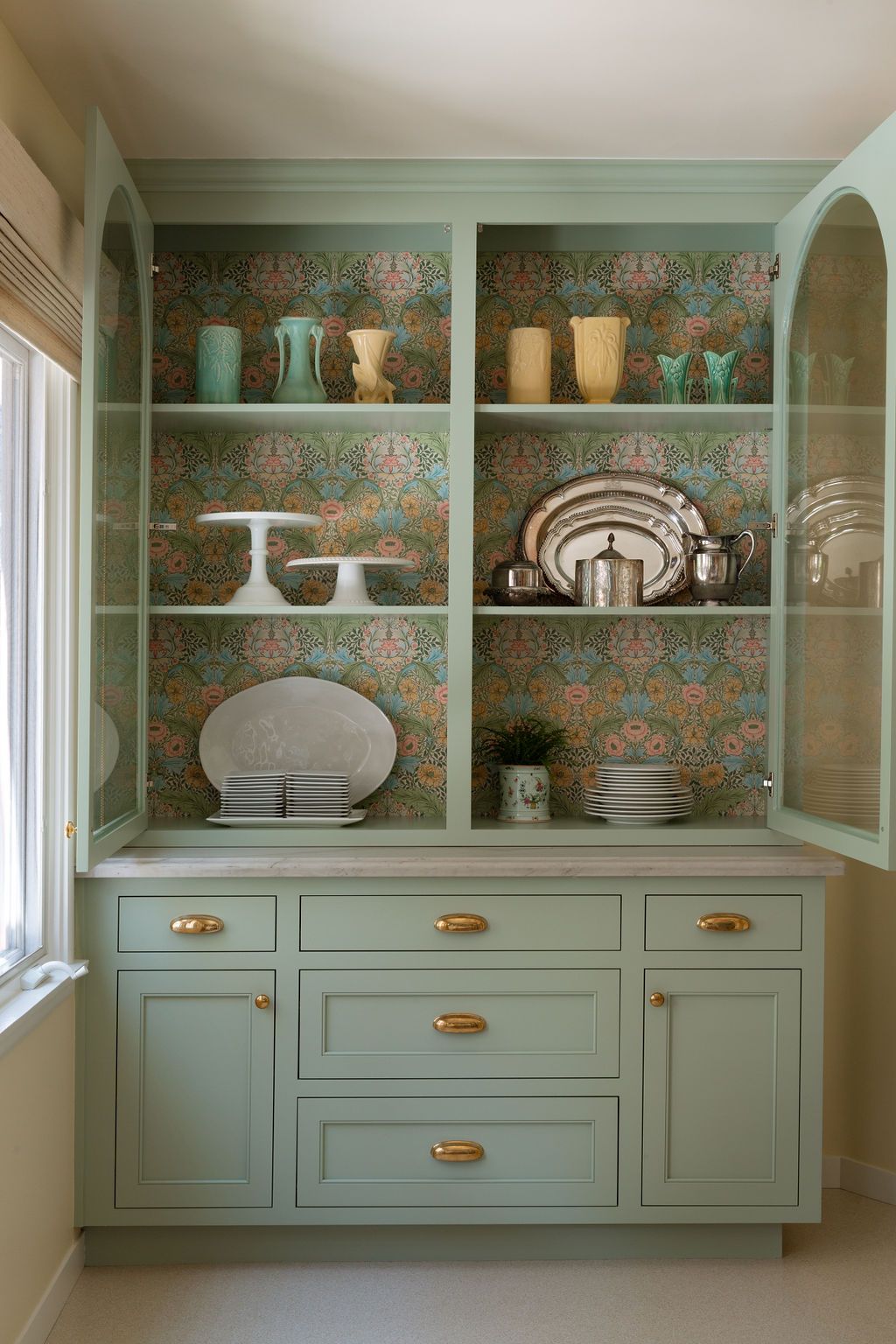 Custom home remodel built-in hutch with sage green cabinetry and open shelving displaying dishware.
