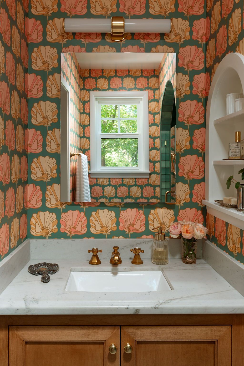 Luxury bathroom remodel featuring floral wallpaper, white sink, and gold fixtures.