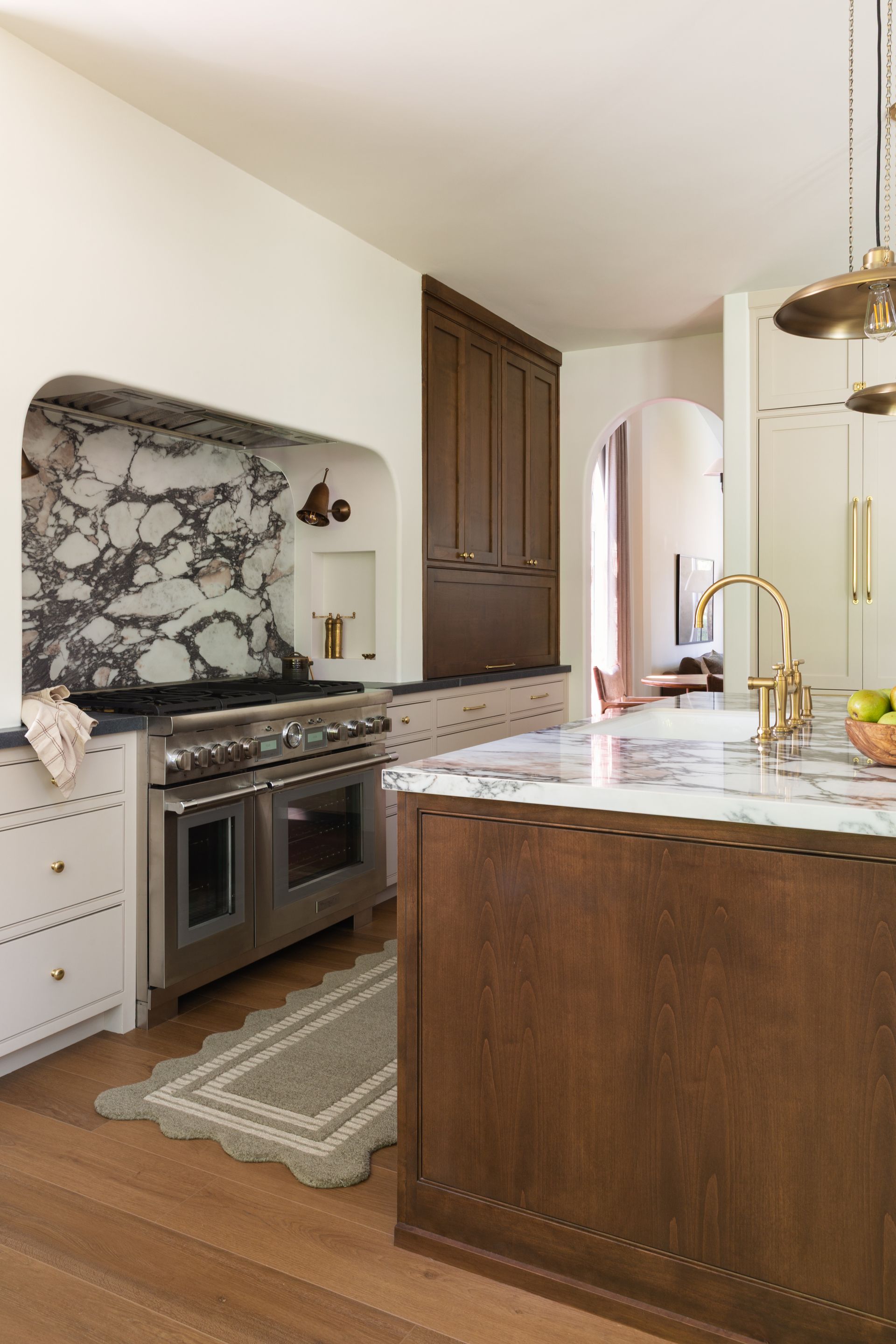 Kitchen addition detail showing dark wood and cream upper cabinets beside an arched marble backsplash.