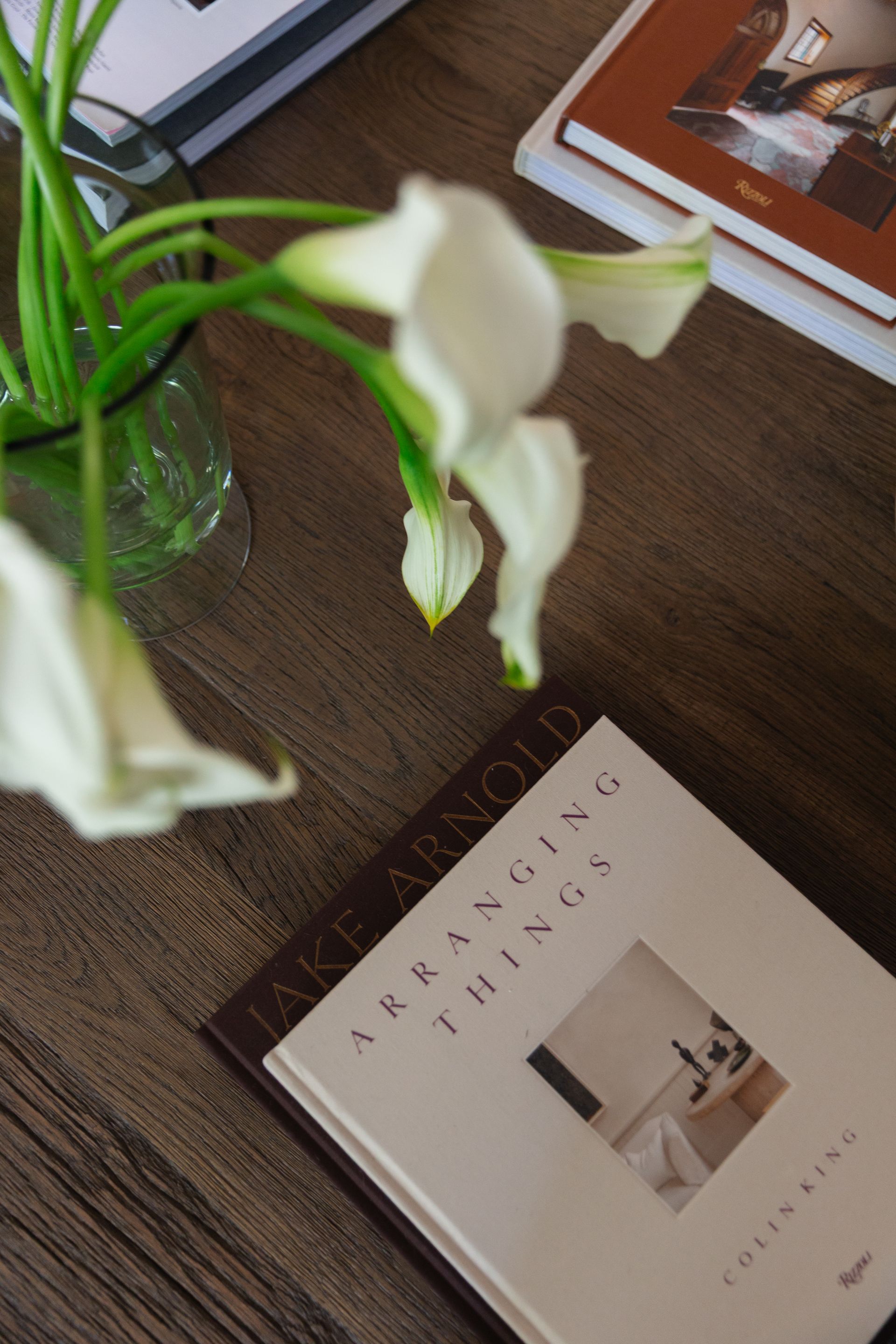 Zoomed-in photo of a wooden desk that has a flower vase full of white flowers.
