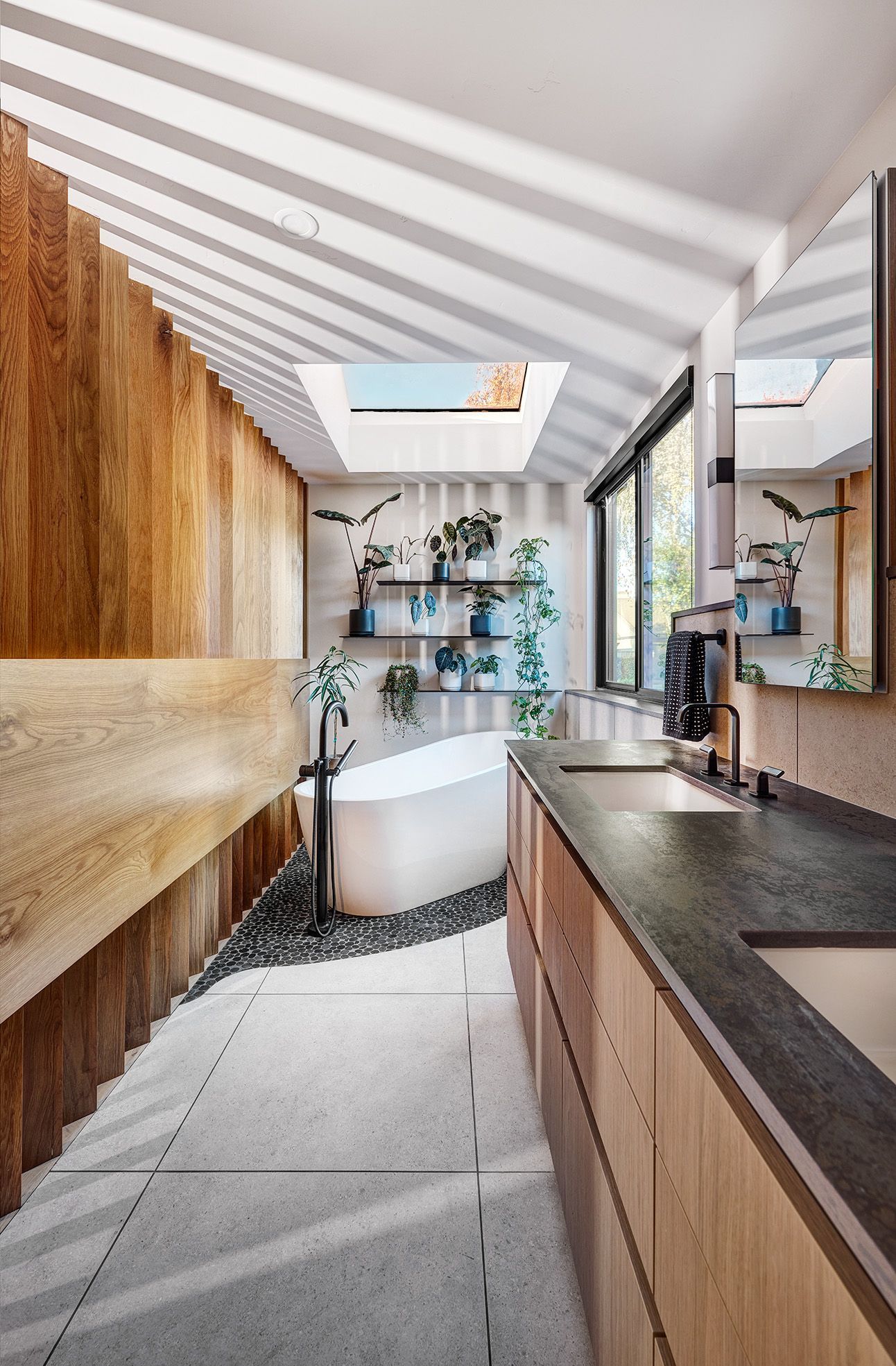 Open bathroom space with wood-paneled walls, a freestanding tub, and skylights.